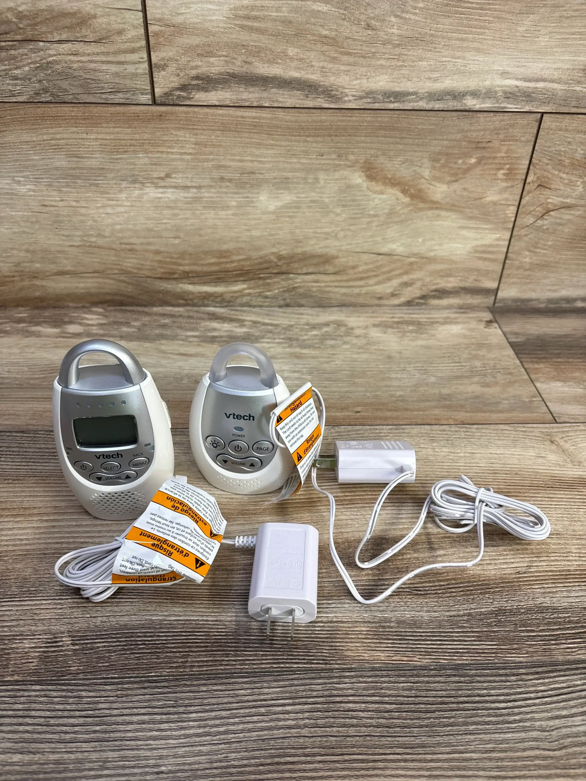 Front view of VTech DM221 baby monitor showing parent unit with LCD, baby unit and power adapters on wood background