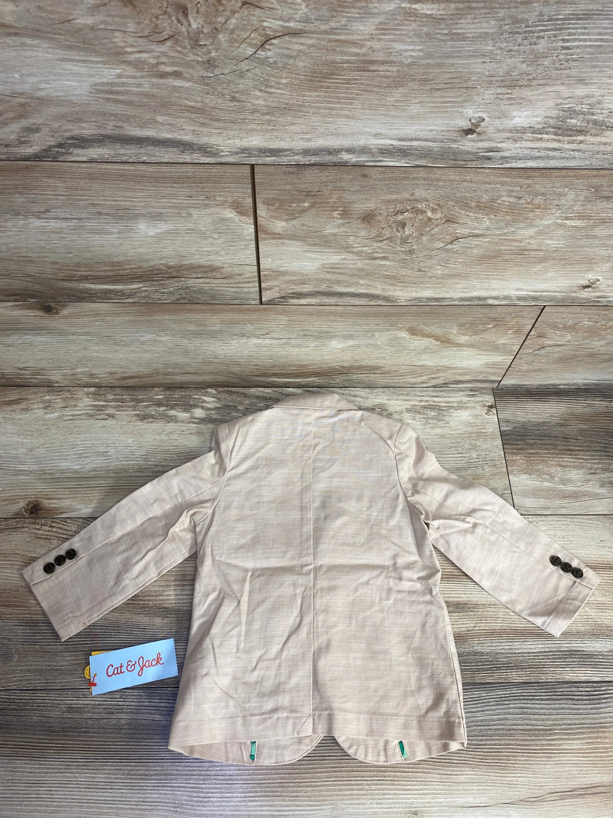 Beige toddler blazer jacket with buttons, displayed flat on wood floor, Cat & Jack tag visible