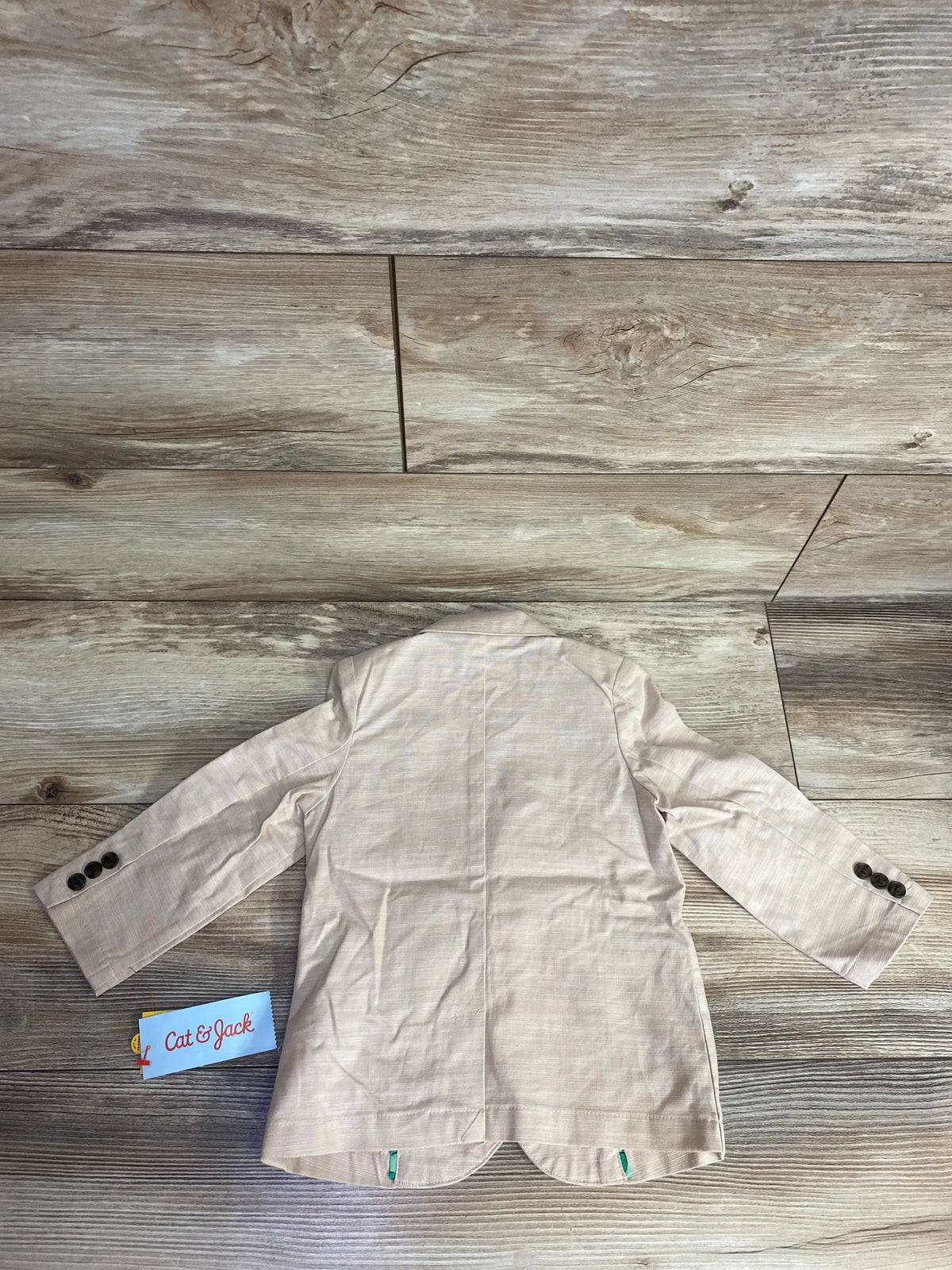 Beige toddler blazer jacket with buttons, displayed flat on wood floor, Cat & Jack tag visible