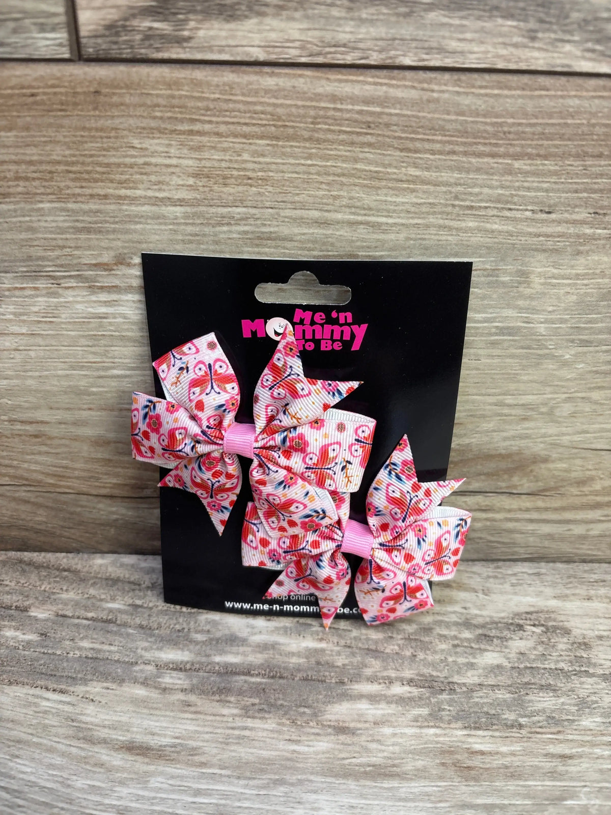 Front view of pink butterfly hair bows 2-pack showing fanned ribbon loops on a black display card over wood background