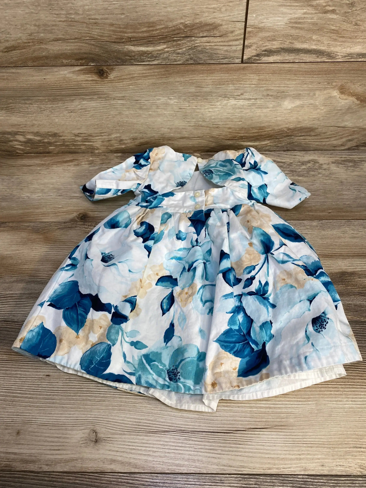 Flat lay of Janie and Jack toddler floral dress (18-24 months) showing blue floral print, puff sleeves, skirt on wood floor