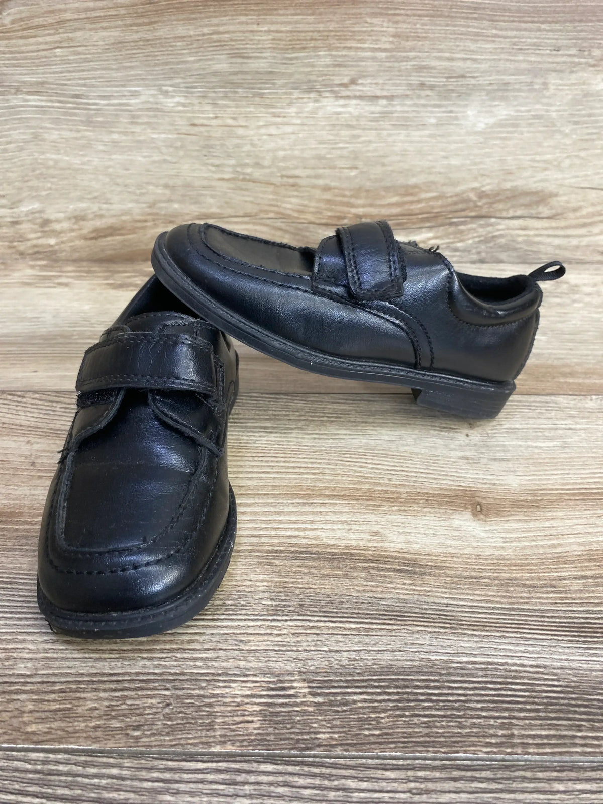Black boys' dress shoes with velcro strap on wooden surface