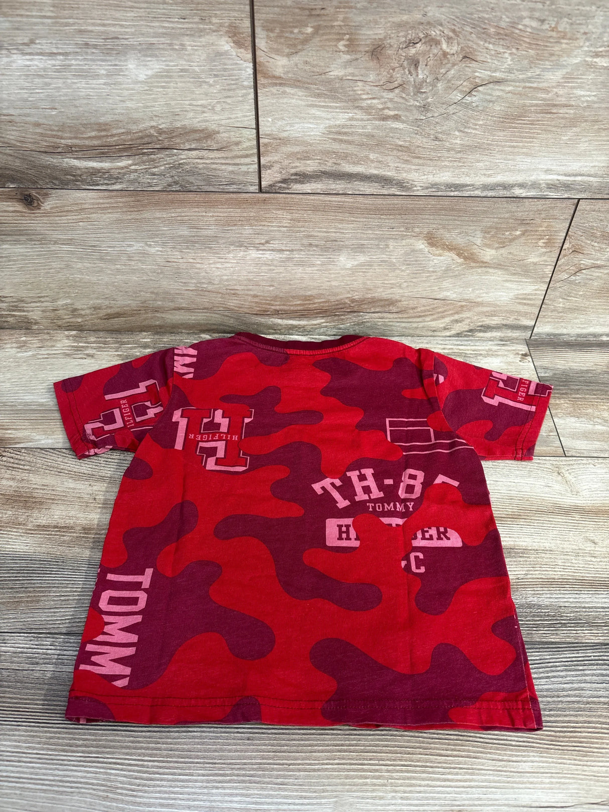 Red and maroon camo toddler t-shirt with Tommy Hilfiger logo and text design on wooden floor