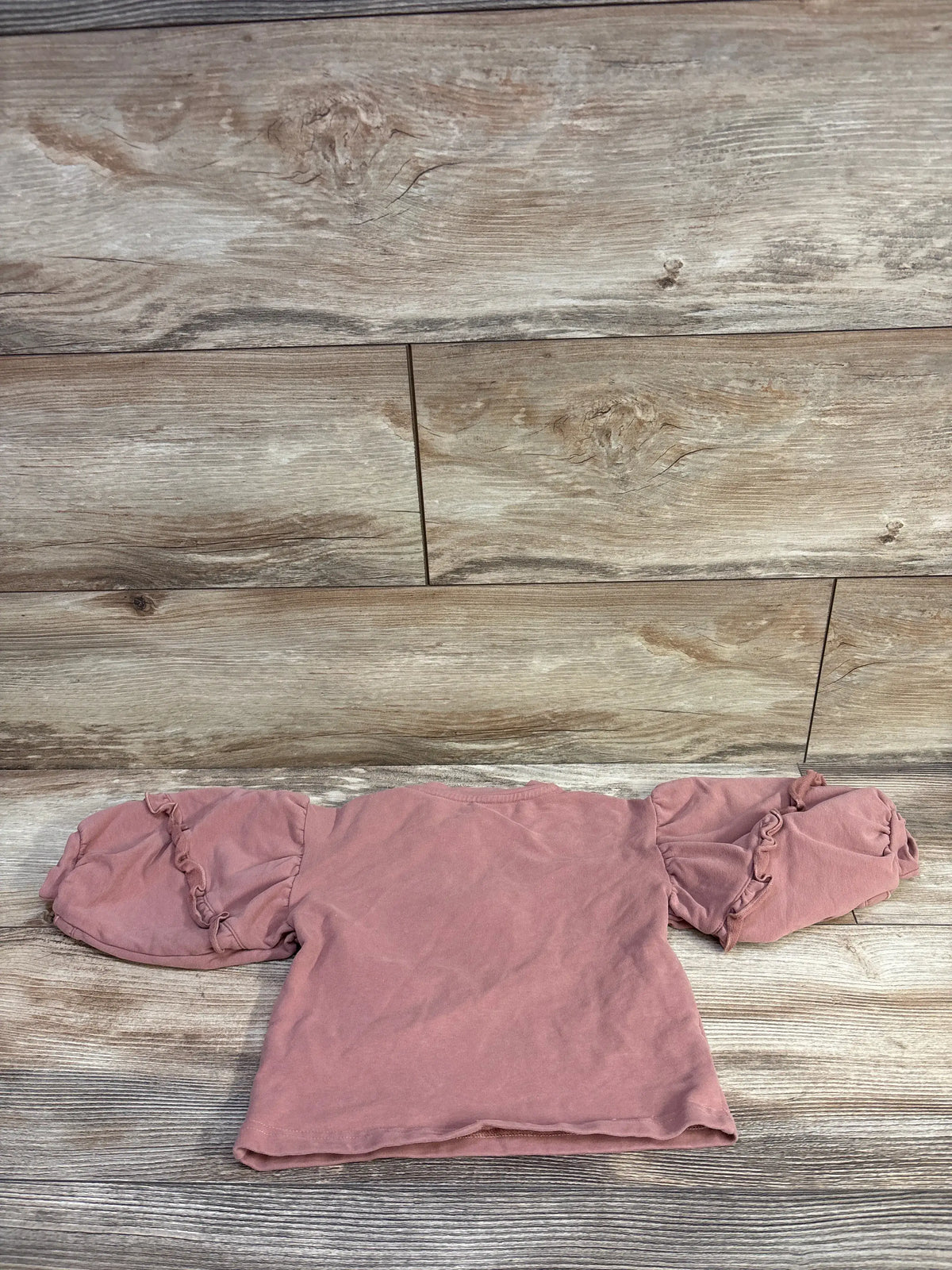 Cherie Kids pink puff sleeve sweatshirt for baby size 6-9m on a wood background