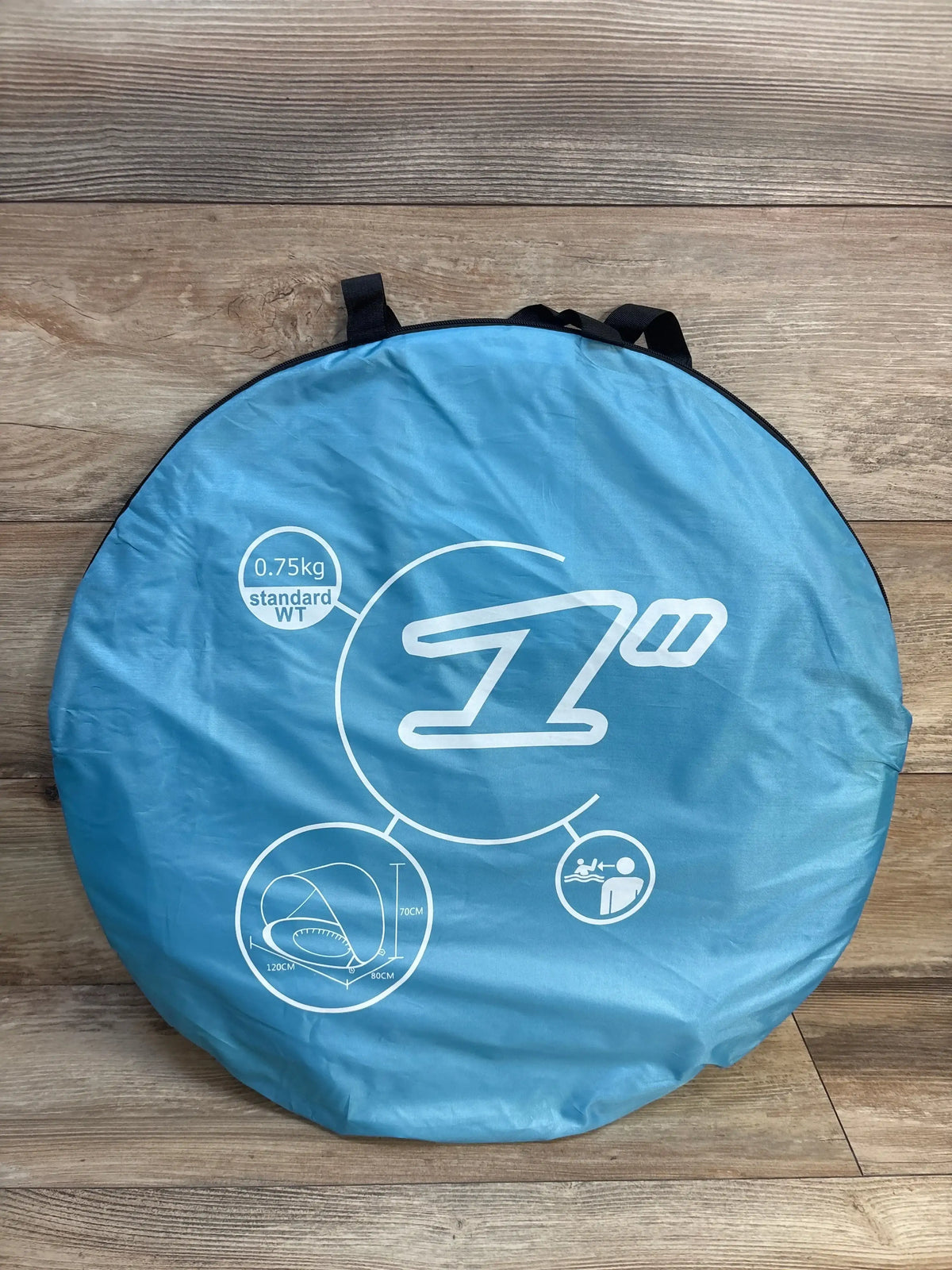 Front view of PandaEar pop-up baby beach tent folded in blue carry bag showing printed 0.75kg and 120x80x70cm with black handles