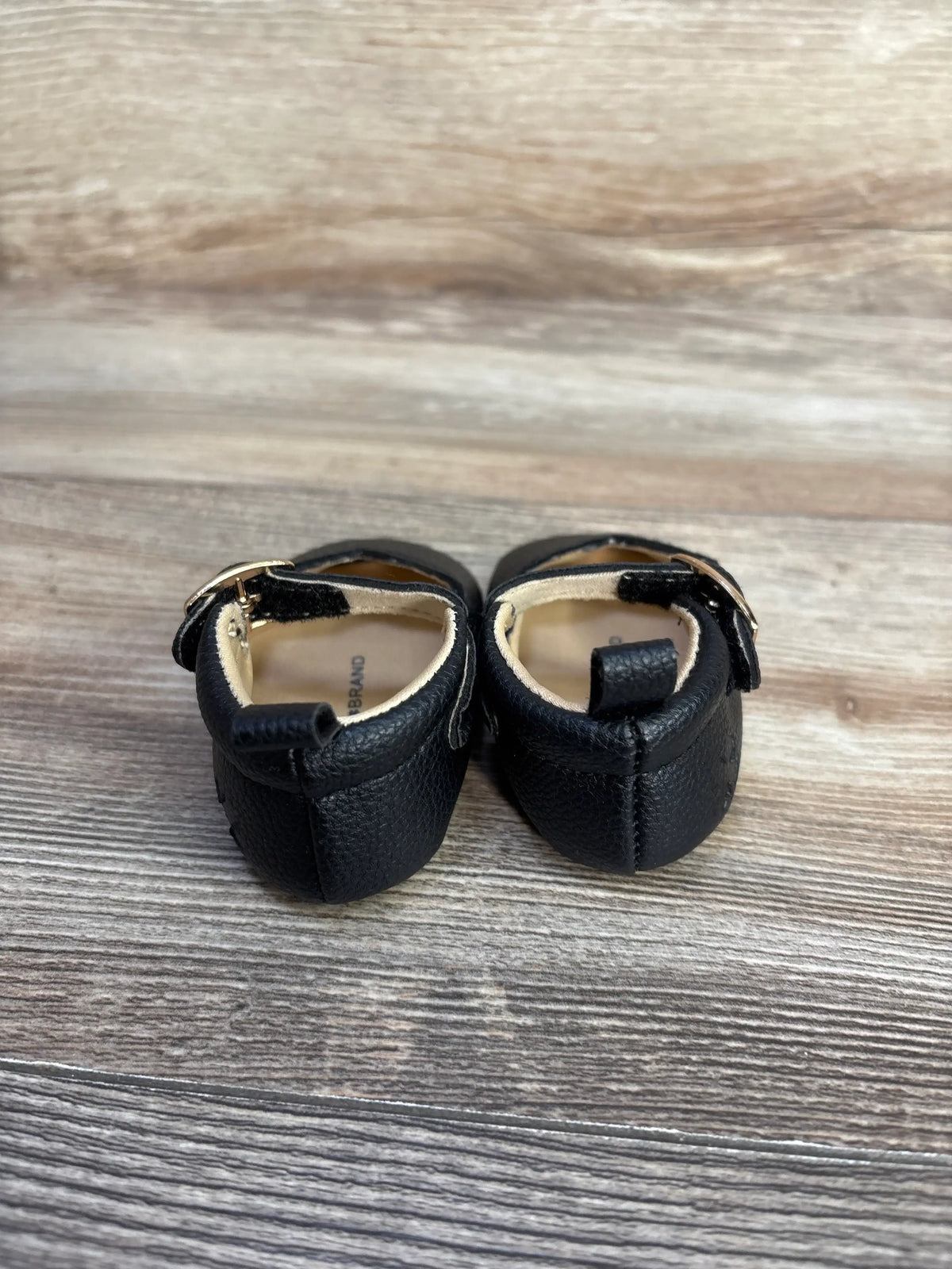 Rear view of black Me n Mommy To Be Mary Jane crib shoes on a wooden surface