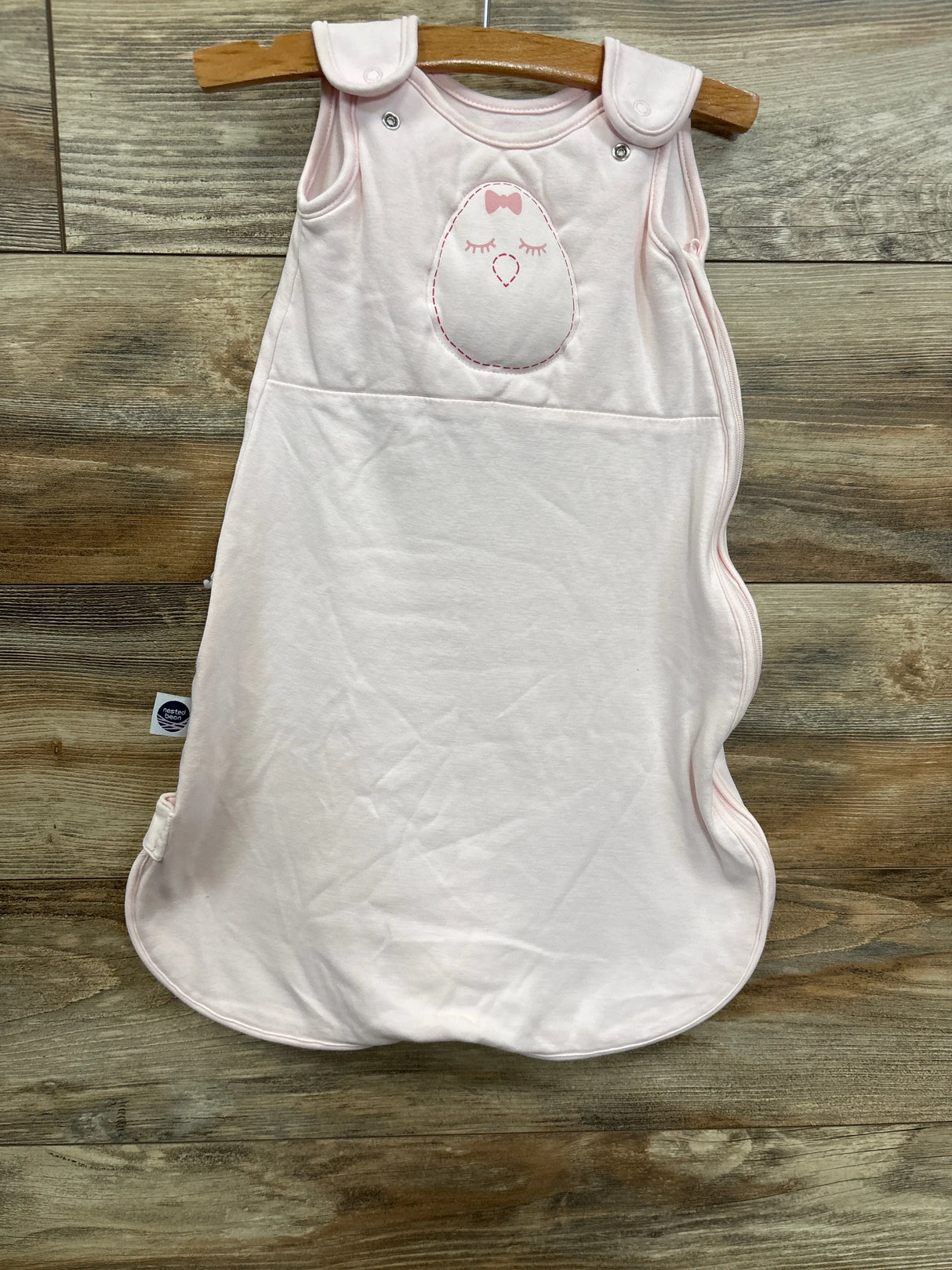 Light pink baby sleeping bag with cute bird embroidery on wood background