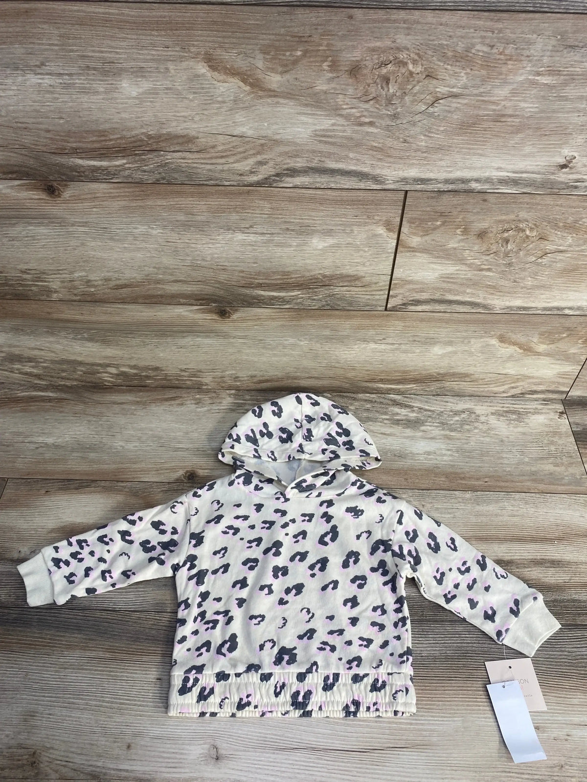 White hooded toddler sweatshirt with gray and light pink leopard print on wooden floor