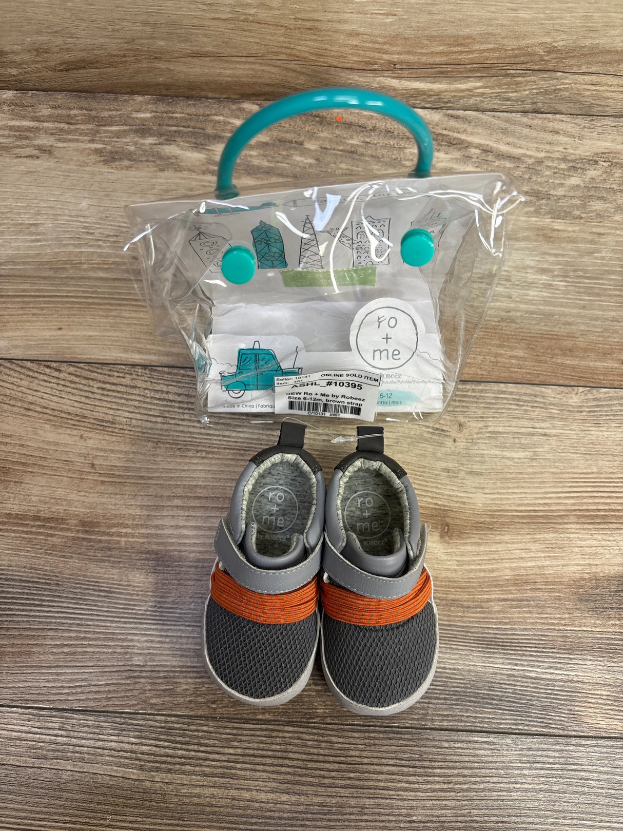 Ro + Me by Robeez gray and orange baby shoes with clear plastic carrying bag on wood floor