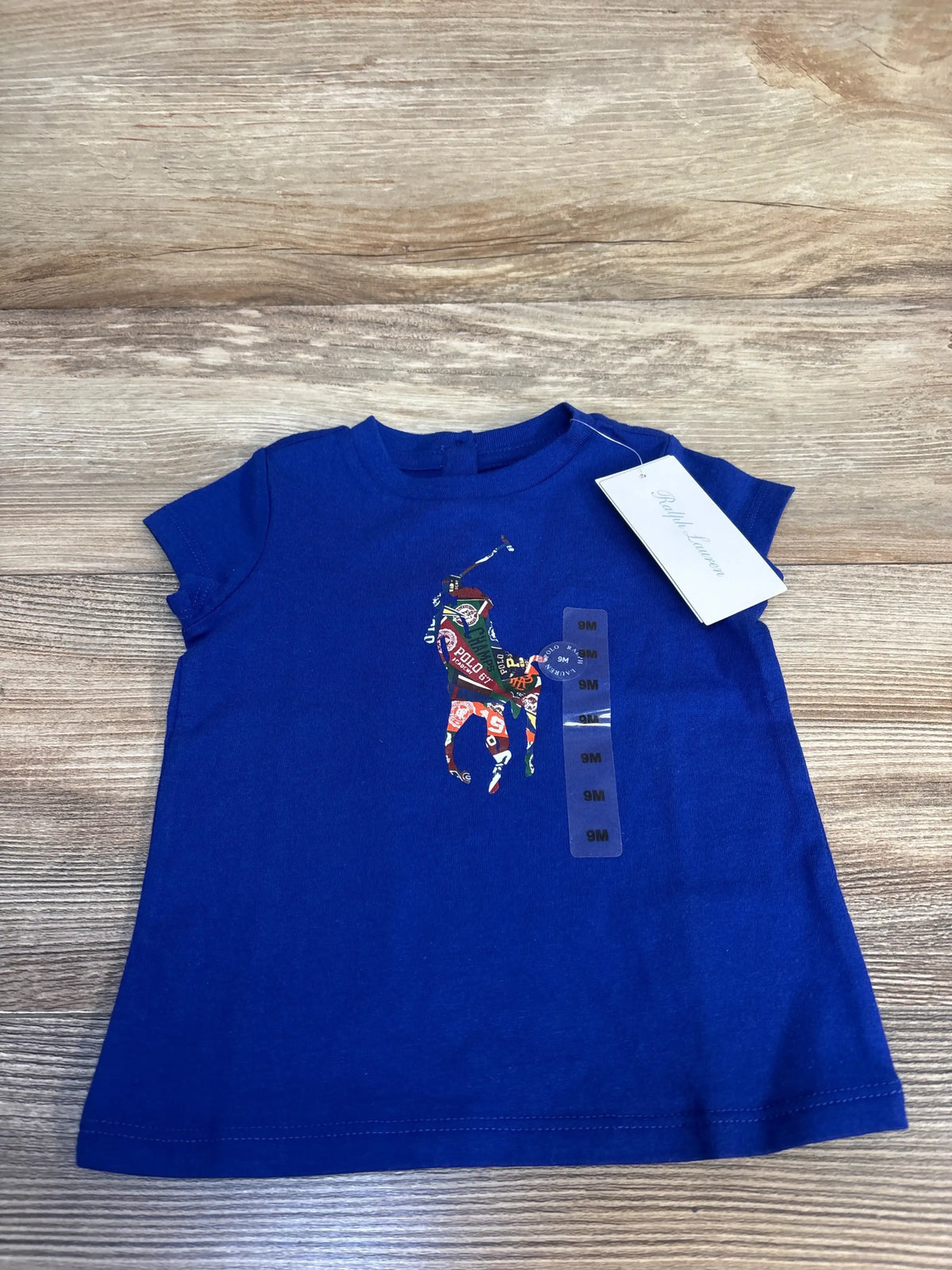 Blue baby t-shirt with colorful polo player graphic, size 9 months, on wood background