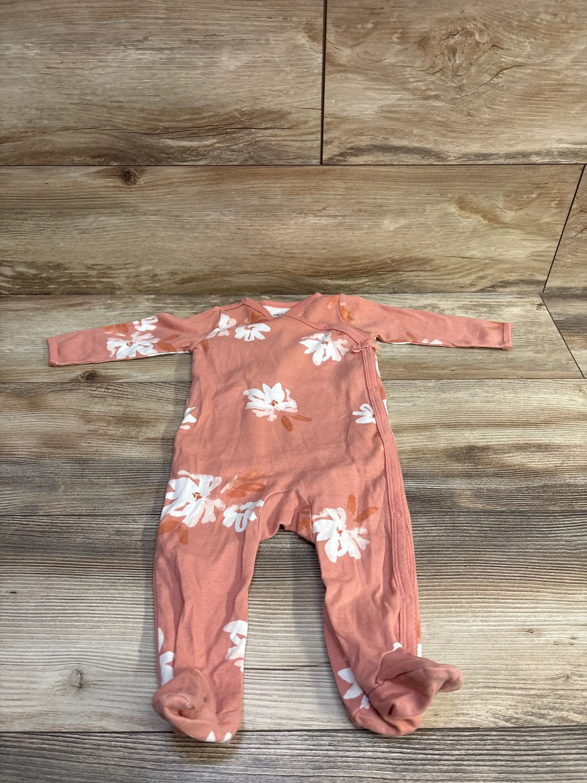 Pink Carter's kimono sleeper for infants with white floral print on a wooden background