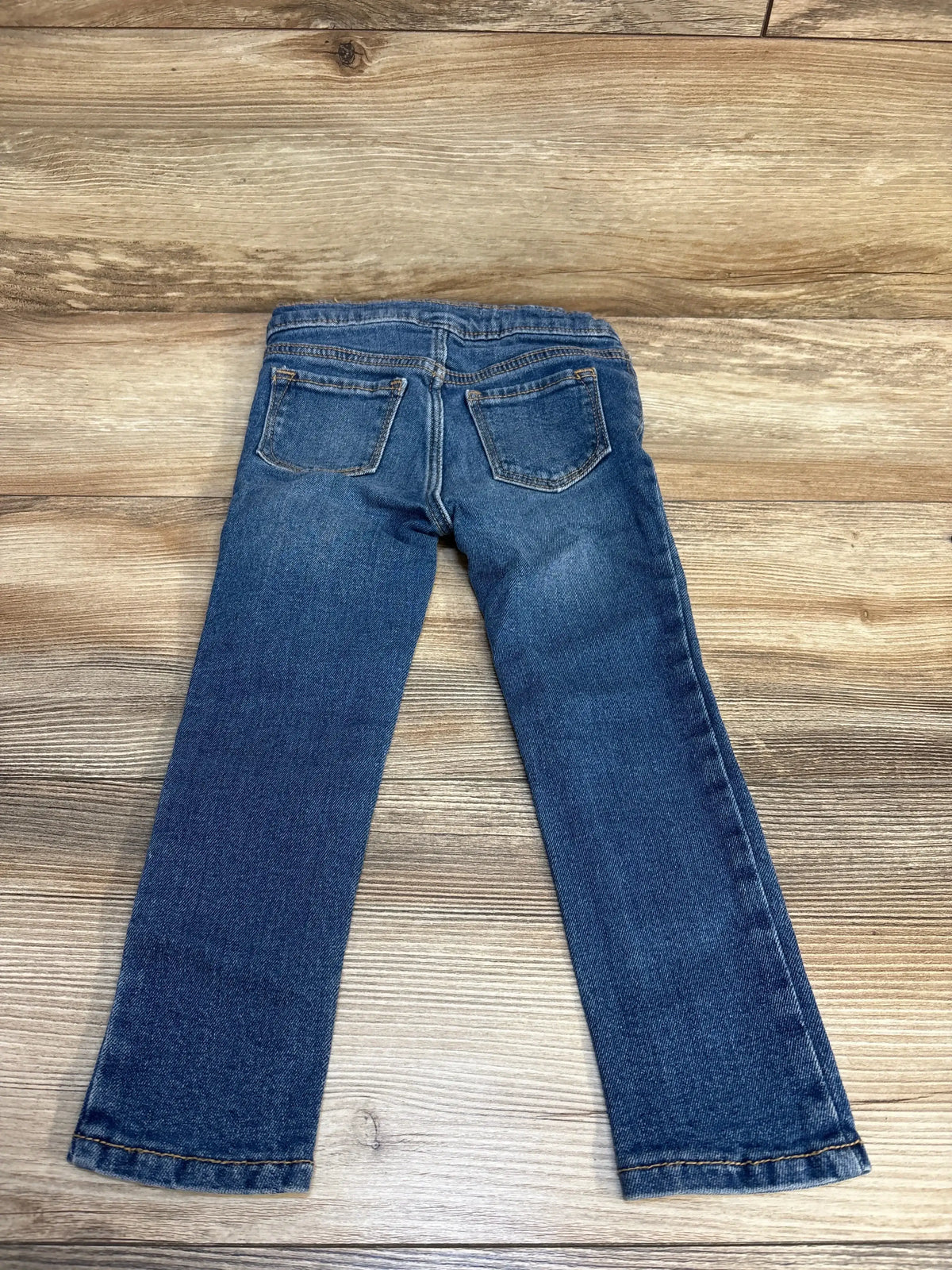Back view of blue kids denim jeans with two pockets on wooden background