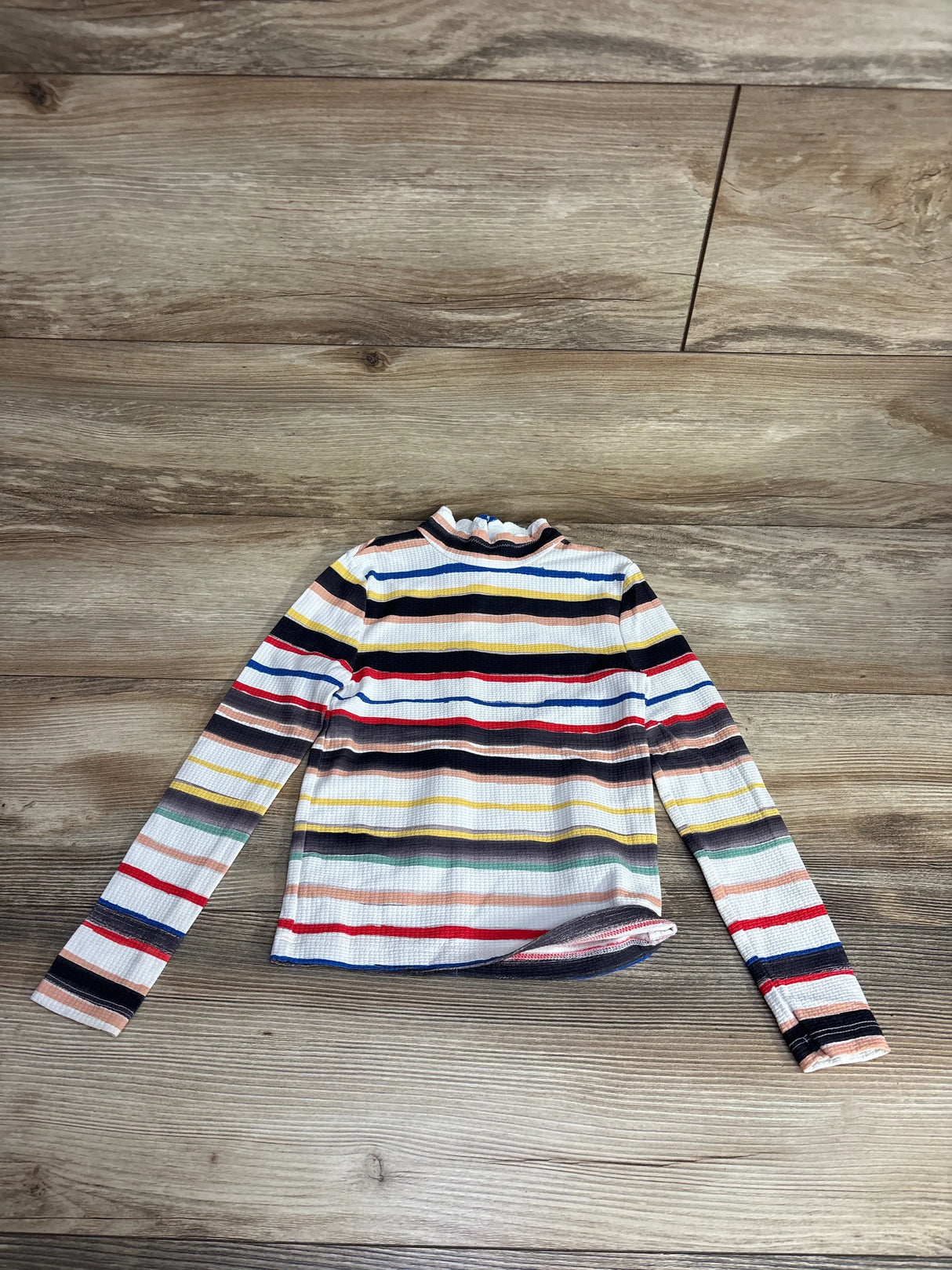 Children's long-sleeve striped mock neck shirt with colorful horizontal stripes on wood floor