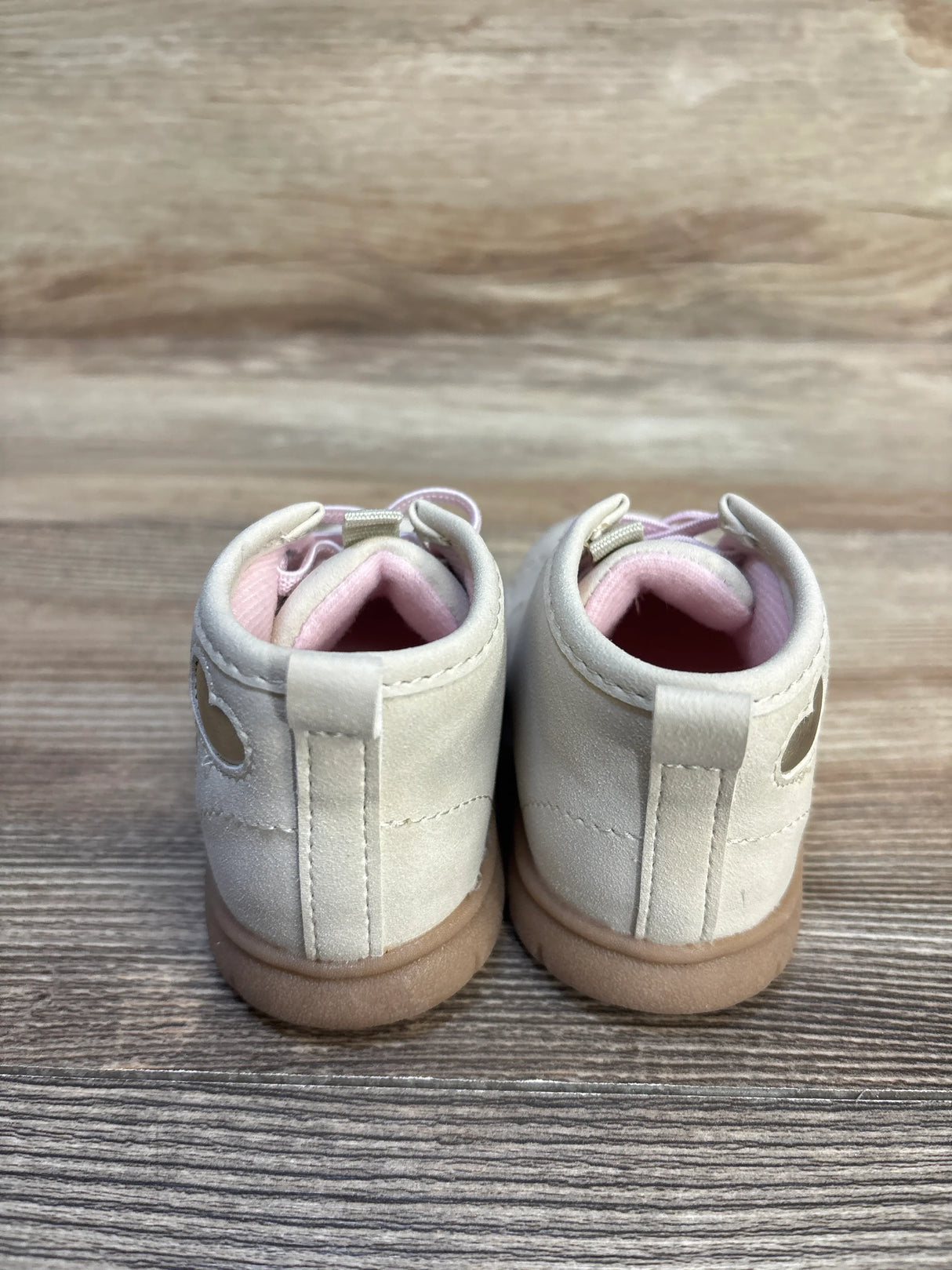Back view of NWOT Just One You Cressida First Walker Boots in tan sz 4c showcasing heart cutout and pink interior on wood plank background