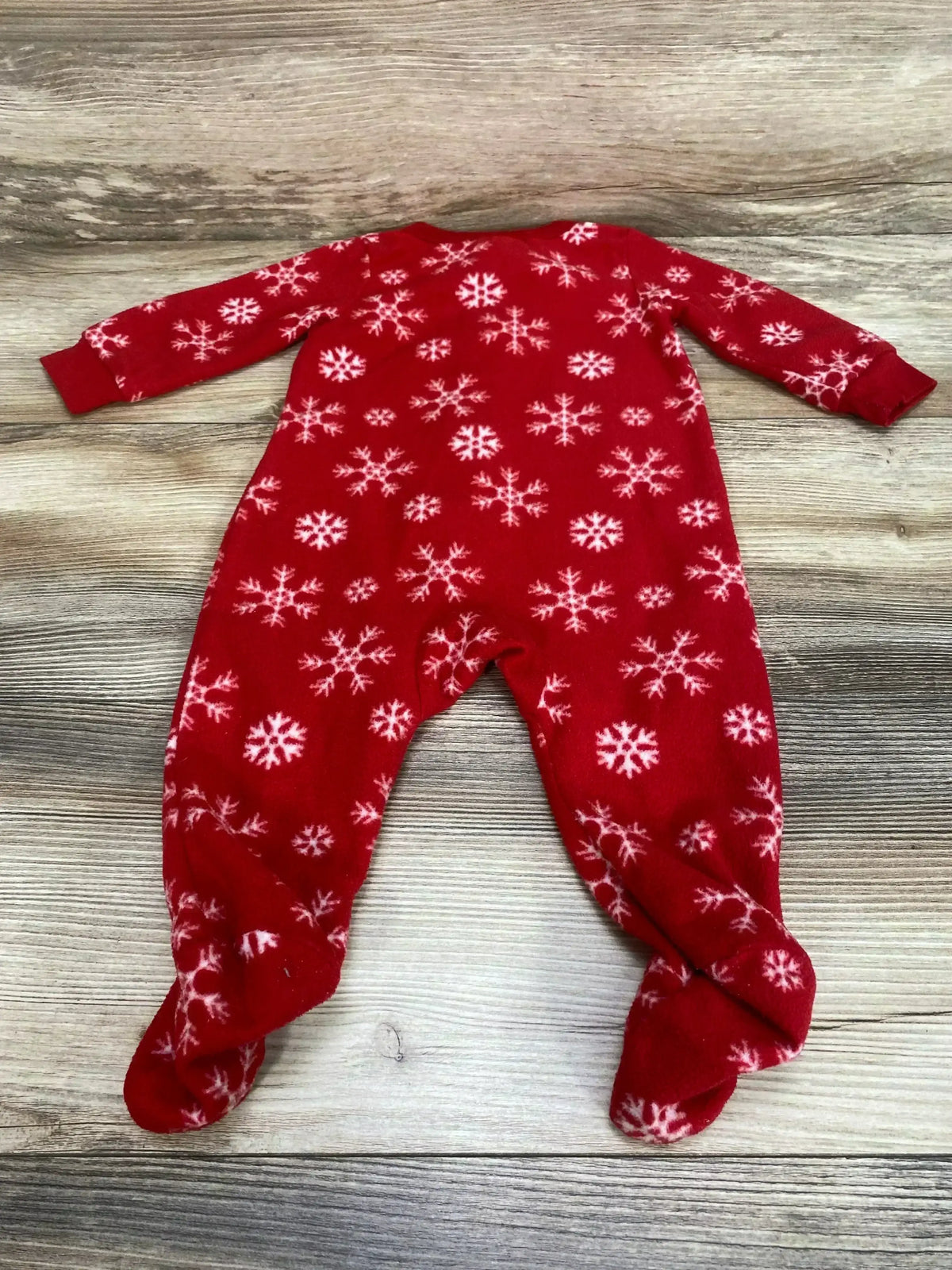 Flat-lay of red snowflake blanket sleeper size 3-6 months showing footed legs and long sleeves on wood background