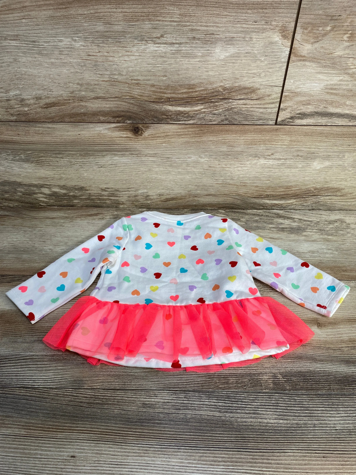 Back view of Cat and Jack white sweatshirt with multicolored heart print and pink tulle peplum on wood background