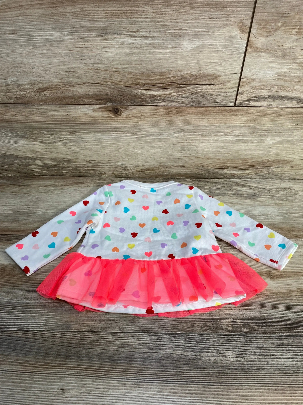 Back view of Cat and Jack sweatshirt in white with multicolor heart print showcasing pink tulle ruffle hem on wood plank floor