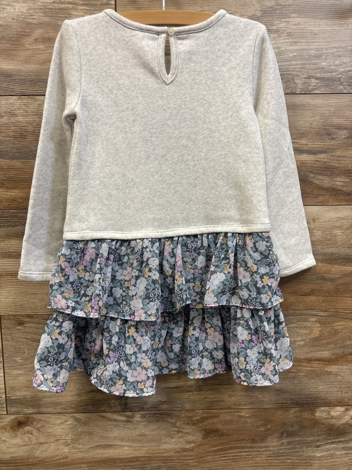 Front view of Oshkosh grey sweatshirt dress size 5T with long sleeves and a floral tiered skirt on a wooden hanger