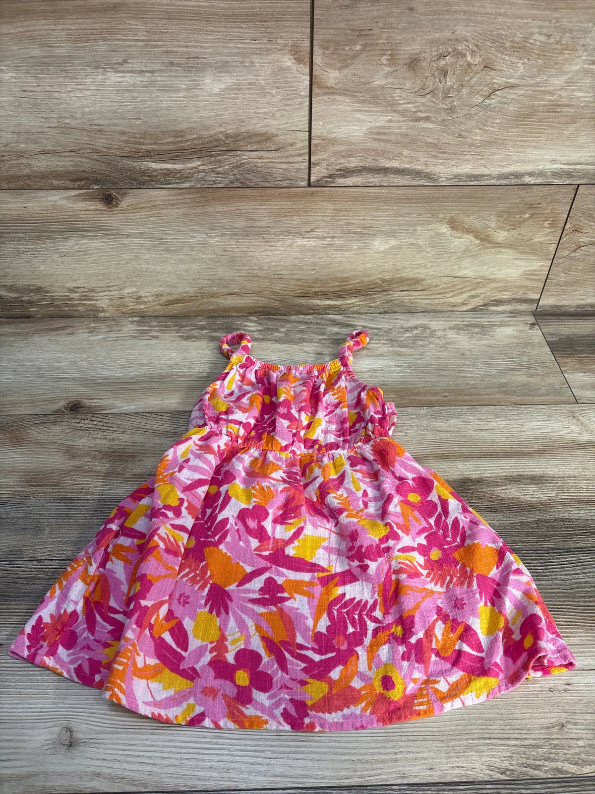 Front view of Cat & Jack pink tank dress showcasing floral print and sleeveless design on a wood surface
