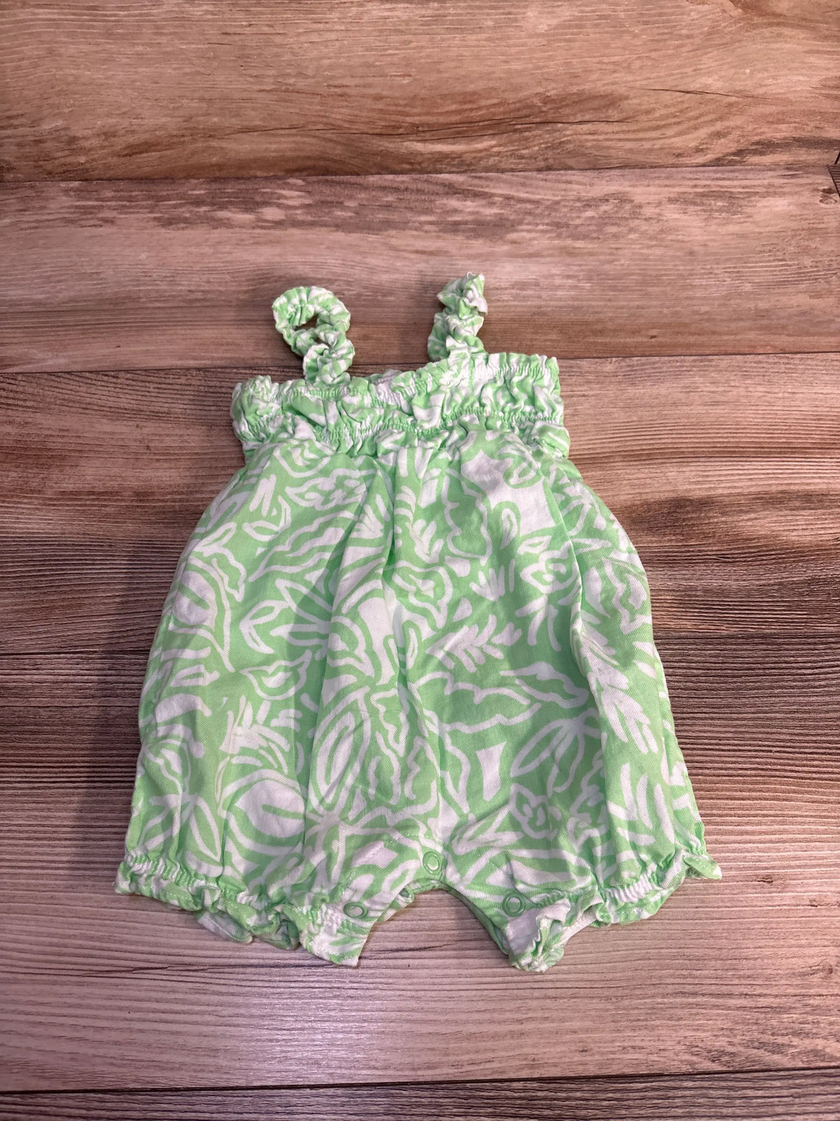 Front view of Carter’s green tank shortie romper showcasing a patterned cotton design and snap closures on a wood background