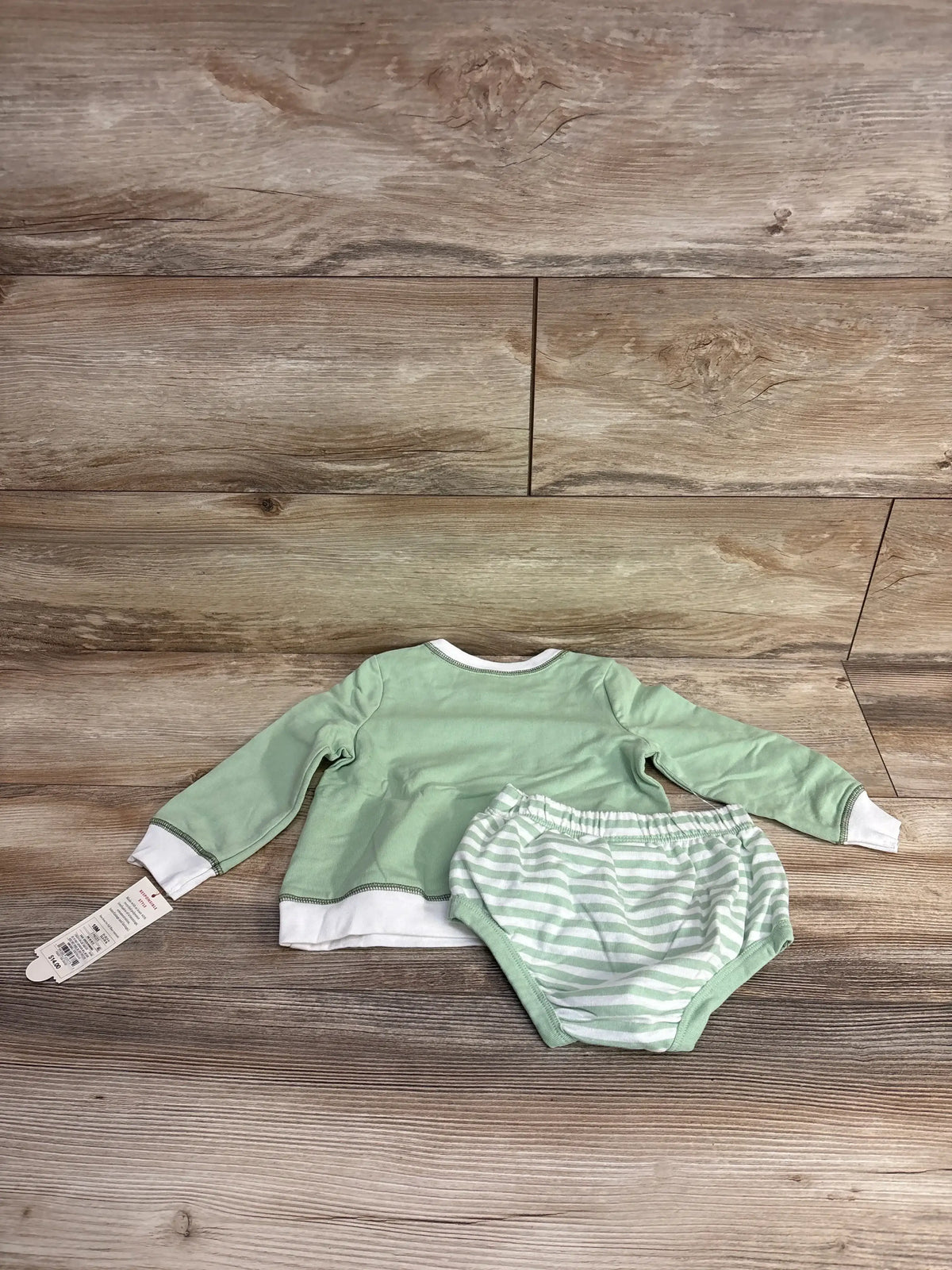 Mint green baby long sleeve shirt and striped diaper cover set on wooden floor