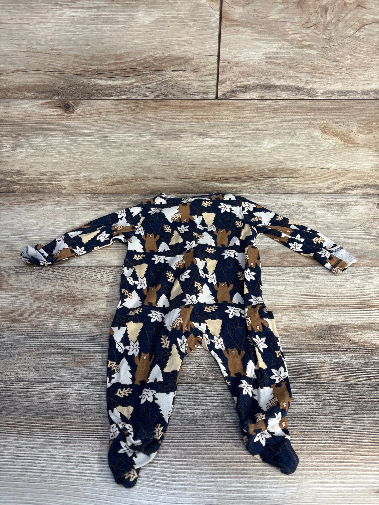 Navy blue baby onesie with bear and tree pattern on rustic wood floor
