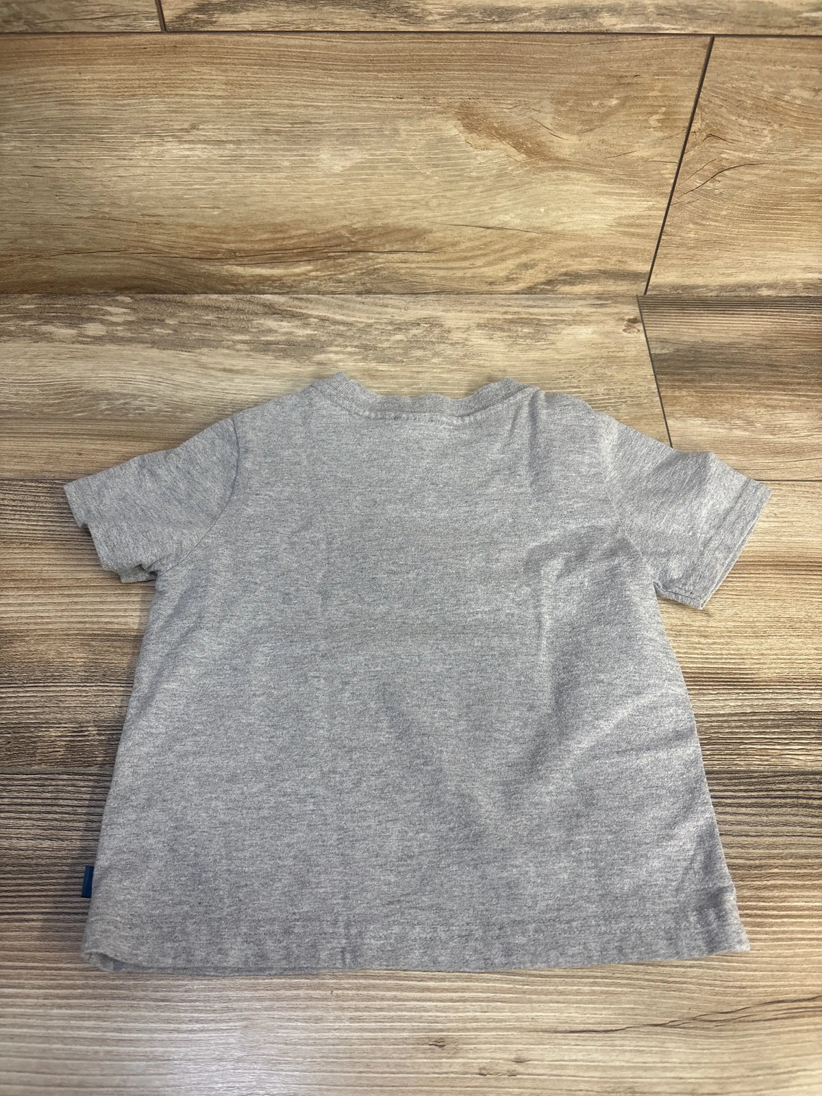 Overhead view of the LA Chargers Touch Down toddler shirt showcasing its grey short-sleeve design with a wood floor background