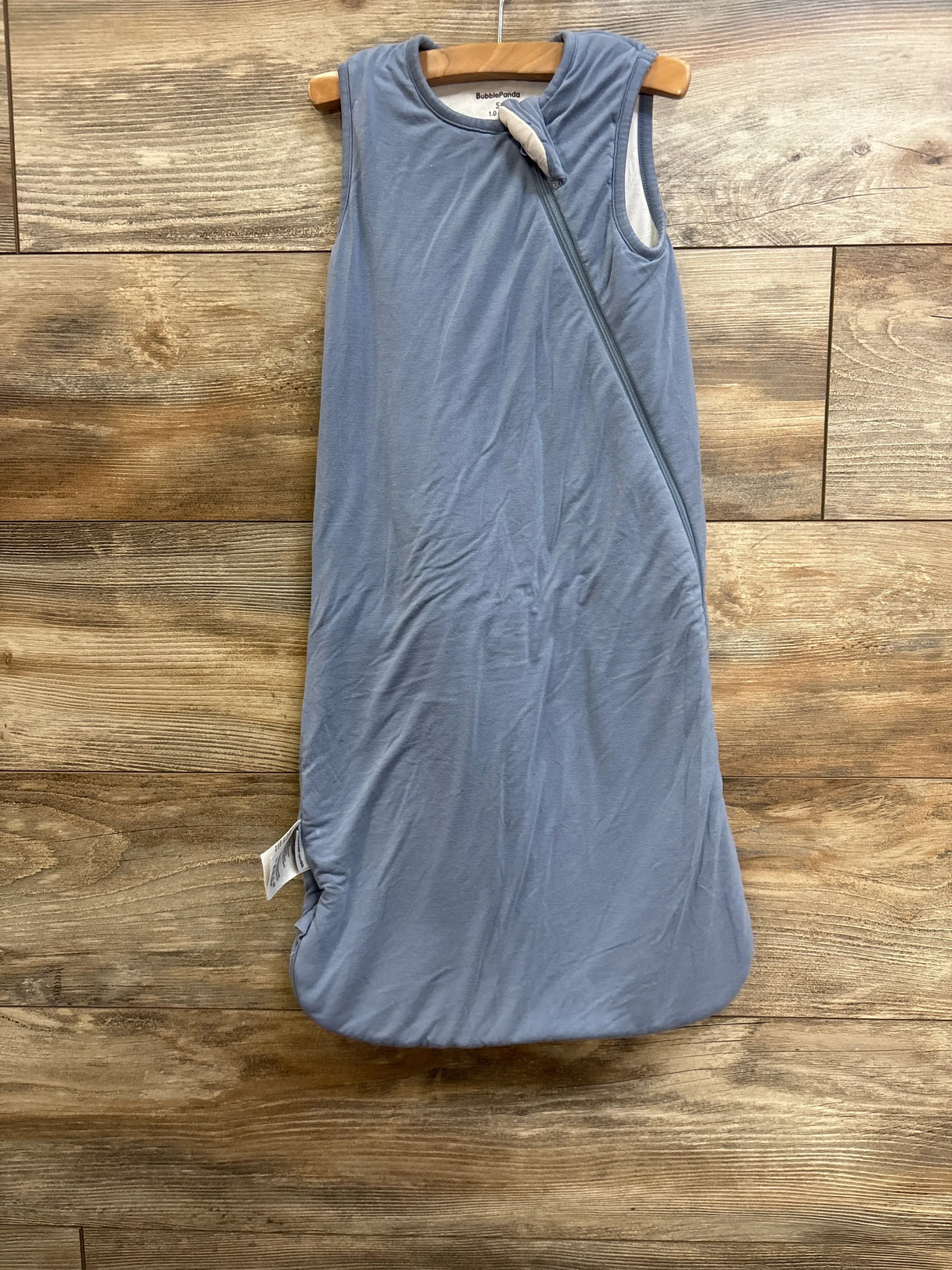 Front view of BubblePanda 1.0 TOG bamboo sleep sack in blue, size 0-6 months, sleeveless with diagonal zipper on wood background