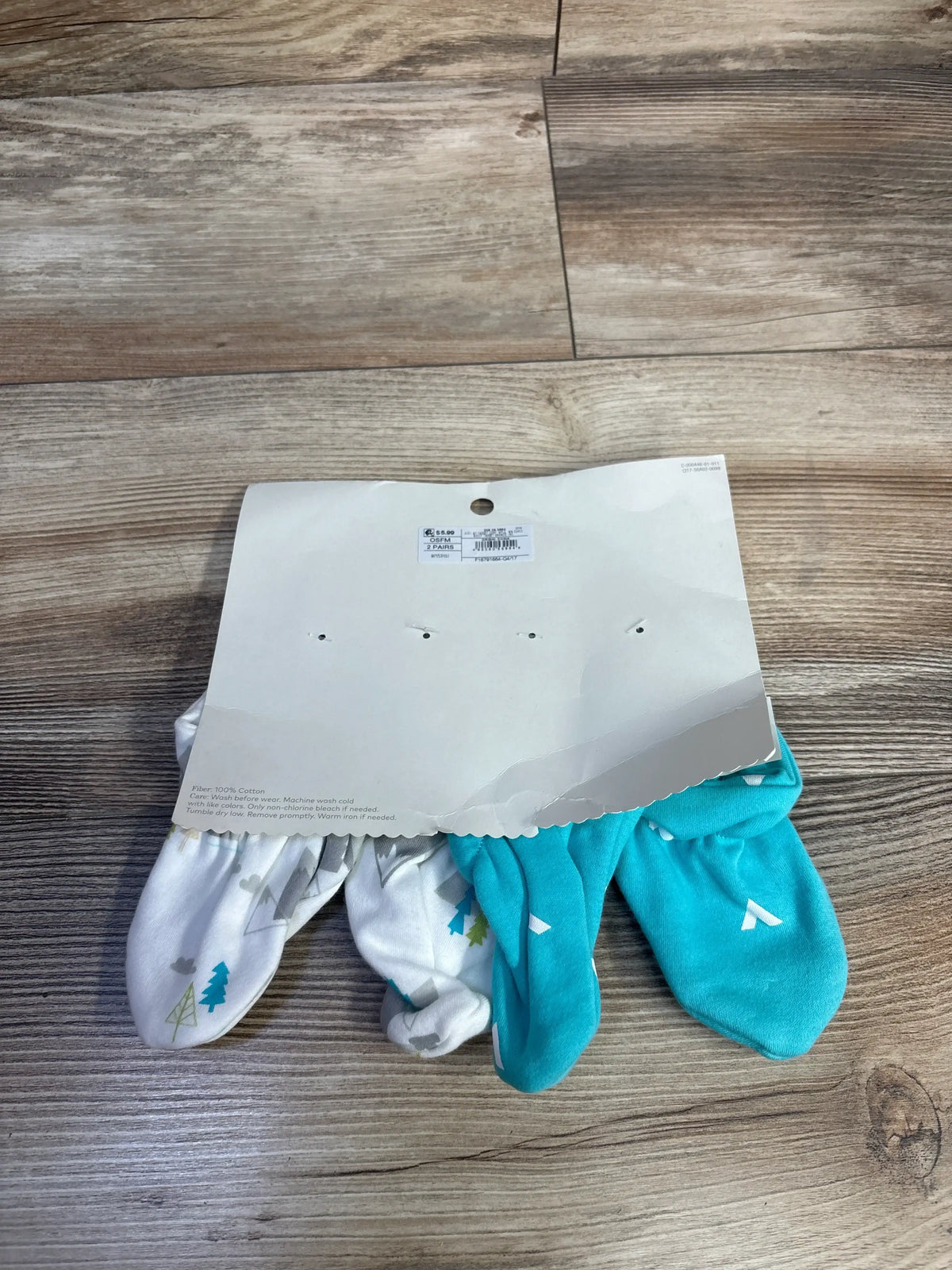Overhead view of Cloud Island 2pk booties showing white patterned and turquoise pairs on cardboard packaging