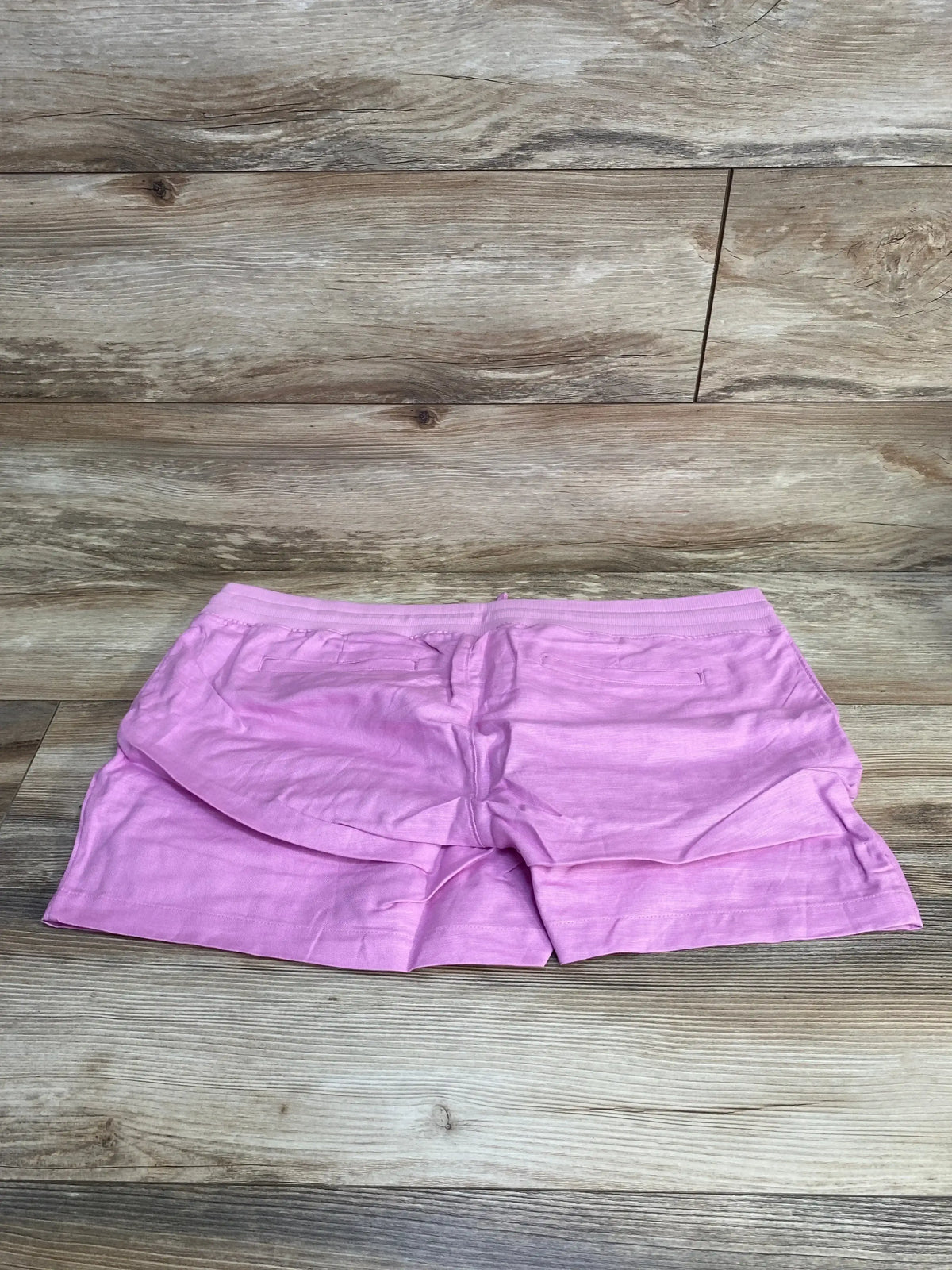 Flat lay of pink Gap maternity linen-cotton shorts, size XL, showing elastic waistband and layered front on light wood background