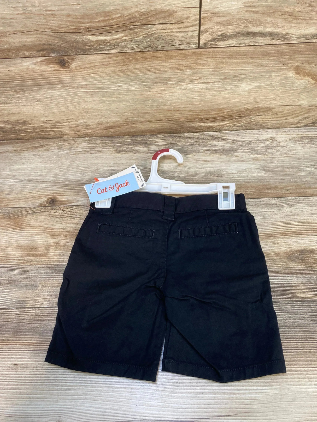 Back view of Cat & Jack toddler black school uniform shorts showing back welt pockets and center vent on light wood floor