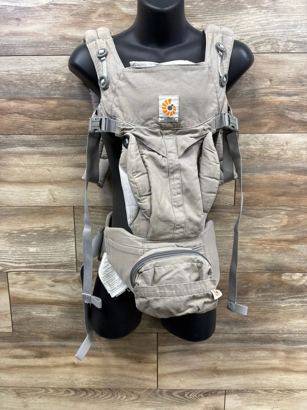Gray Ergobaby baby carrier with adjustable straps and zip pouch on mannequin
