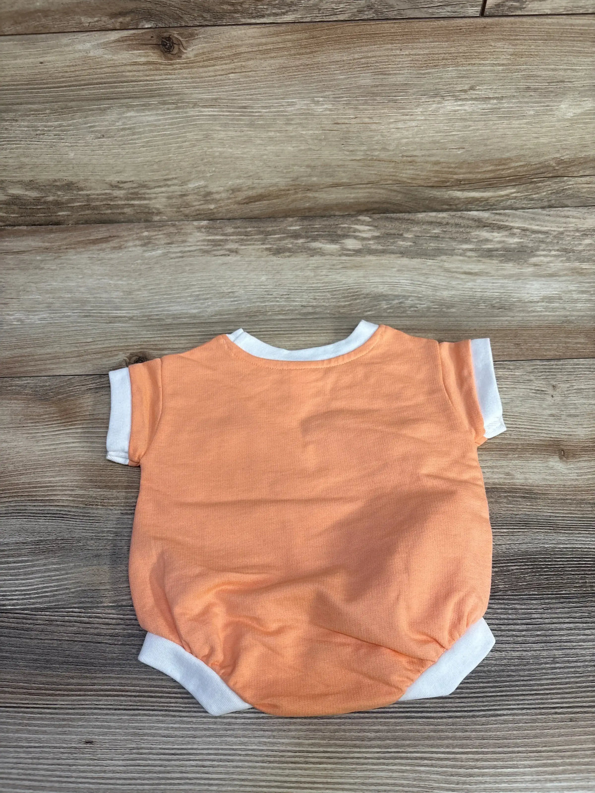 Back view flat lay of newborn Cat and Jack terry romper in orange with white trim and short sleeves on wood background