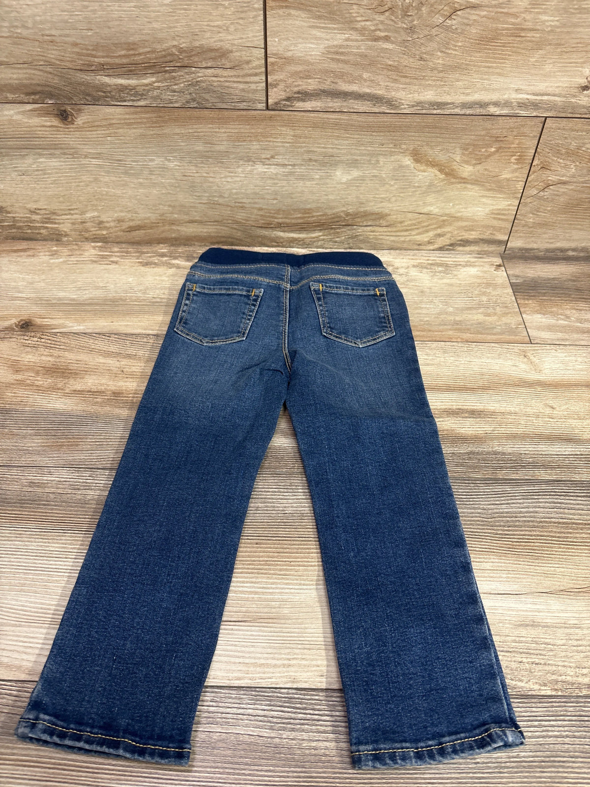 Back view of Old Navy Karate Skinny Drawstring Jeans in blue, size 3T, showing two back pockets on a wood floor