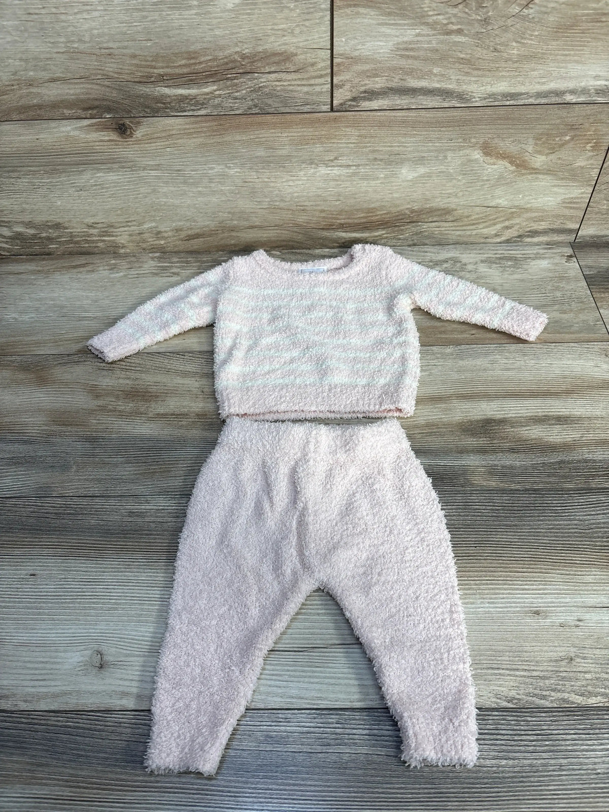 Soft pink baby outfit with long-sleeve sweater and pants on wood floor