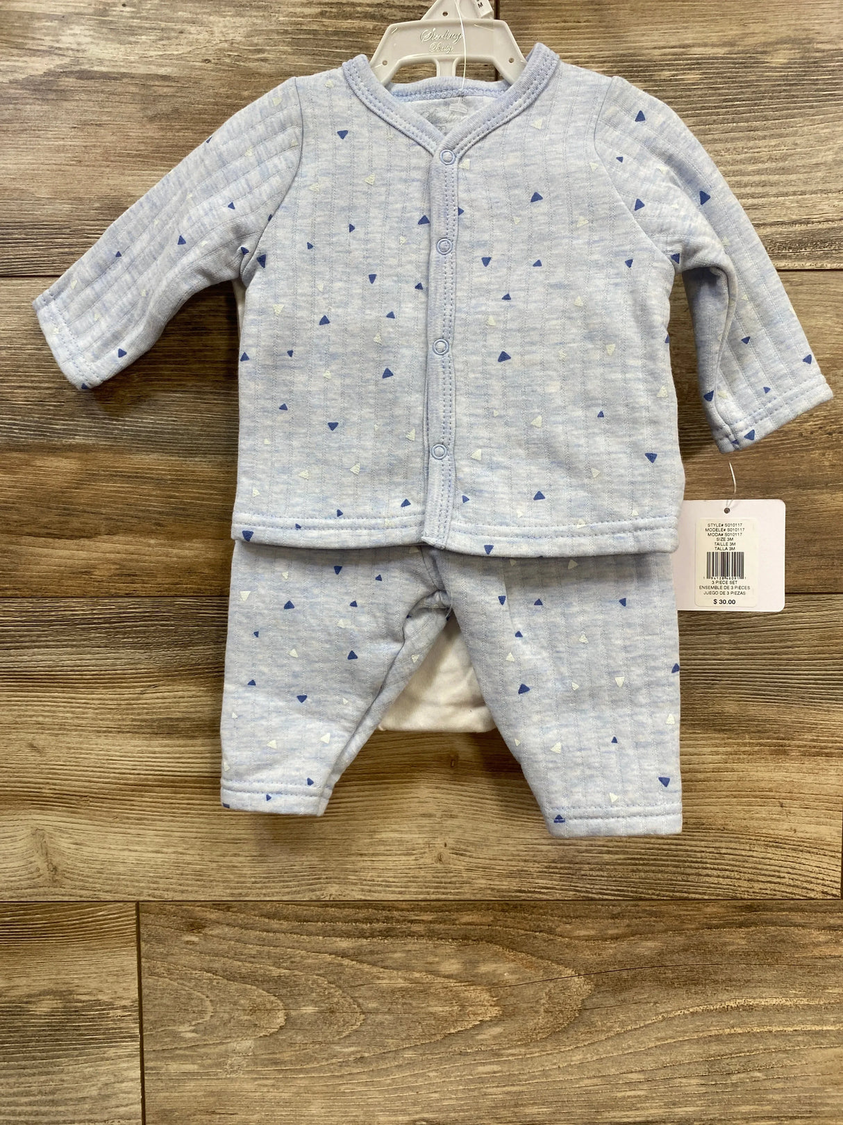Light blue baby outfit set with small triangle patterns on wooden background