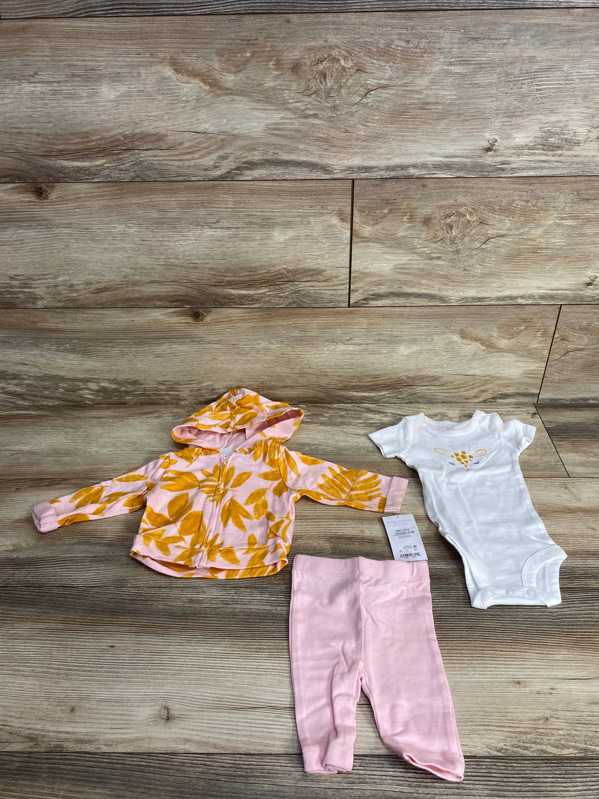 Baby clothing set including pink leaf-patterned hooded jacket, pink pants, and white onesie with giraffe applique