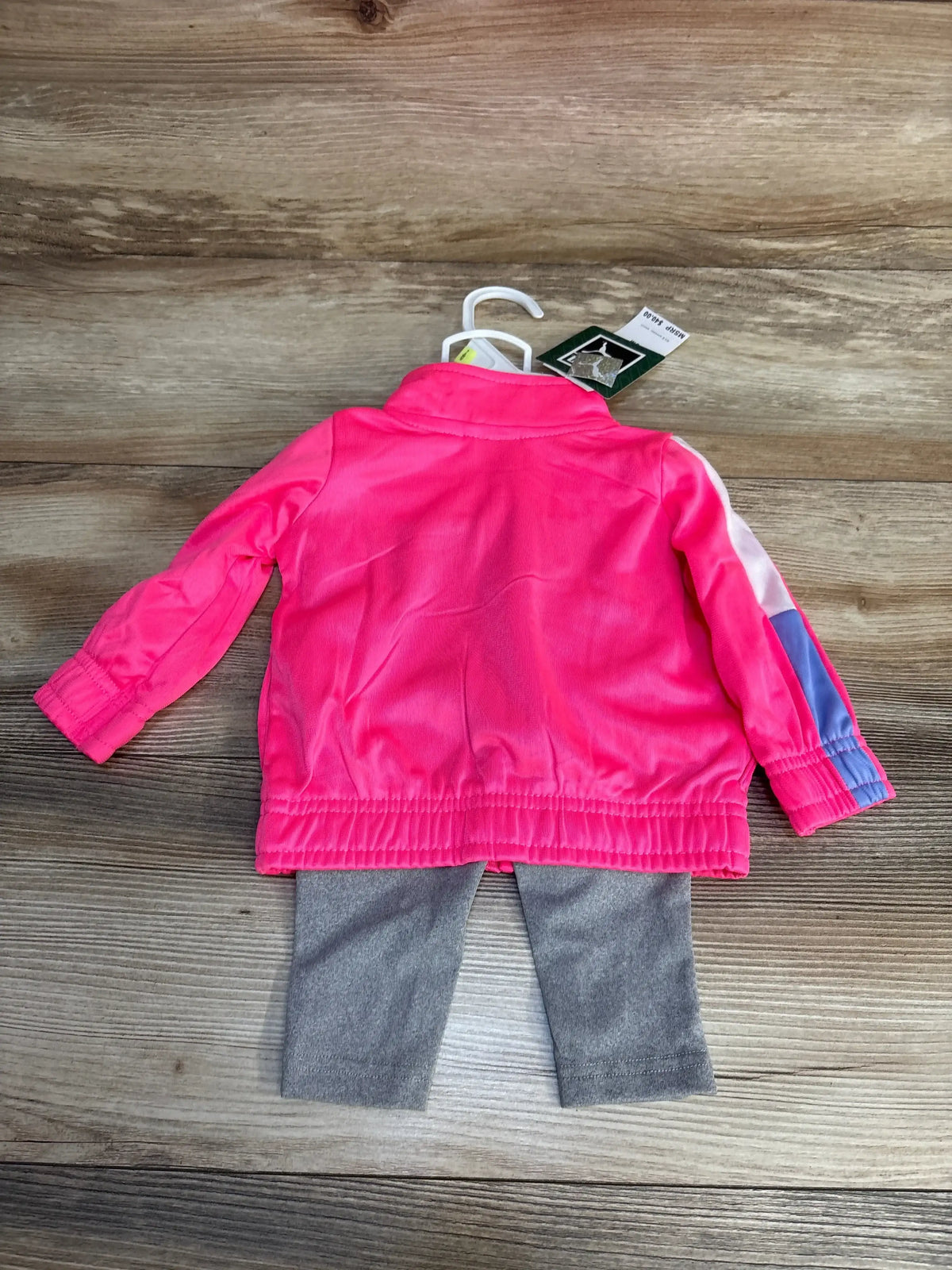 Pink kids track jacket with blue stripe and gray leggings on wood floor