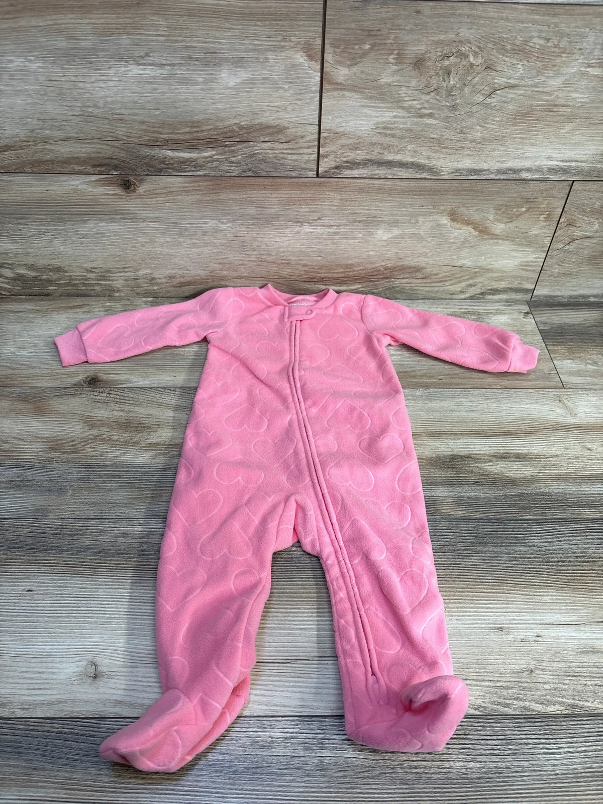 Flat lay of Carter's pink blanket sleeper 9M with front zipper, footed legs, sleeves and quilted heart pattern on wood floor