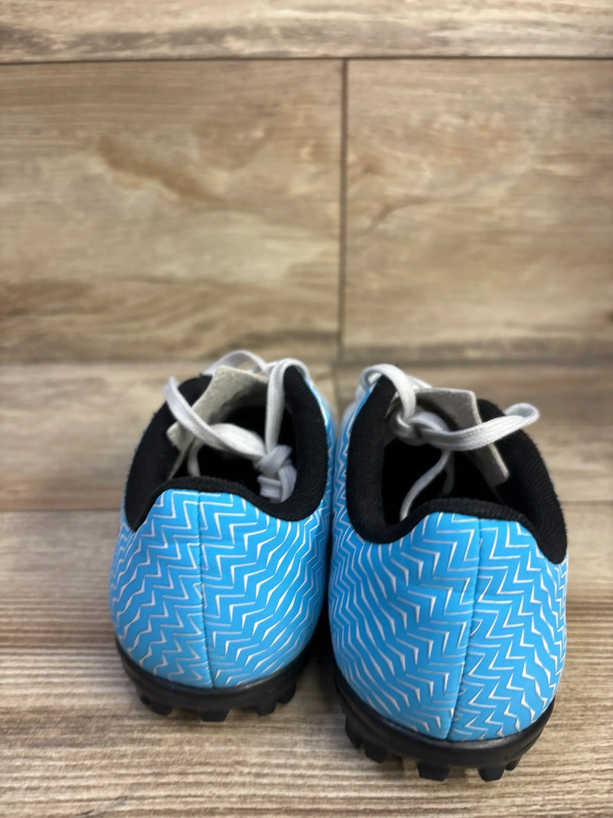 Rear view of toddler blue Puma Rapido II cleats with white zigzag pattern, black collar, white laces and turf studs