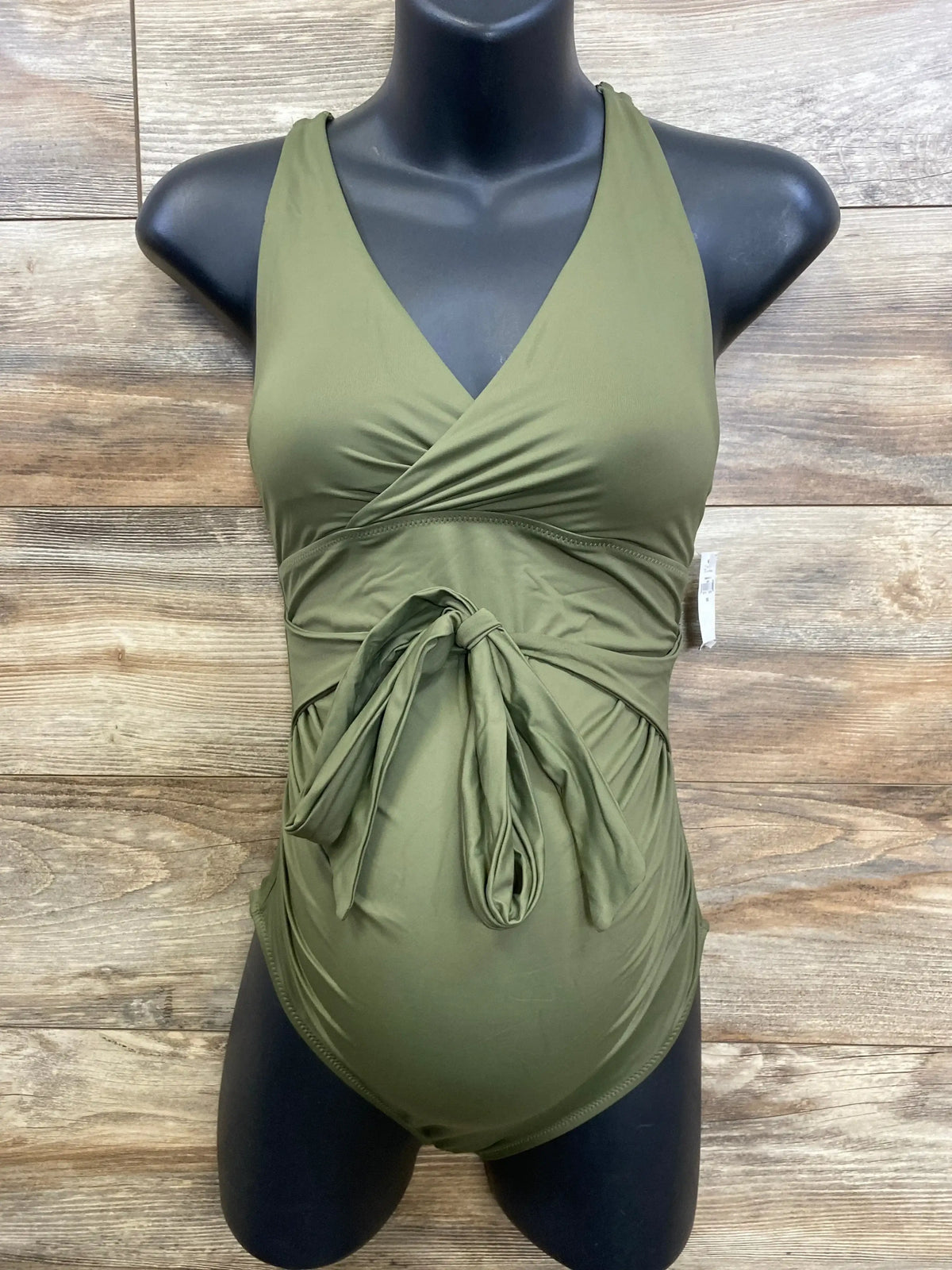 Front view of new Gap Maternity wrap V-neck swimsuit in olive green with tie front on dress form over wood plank floor