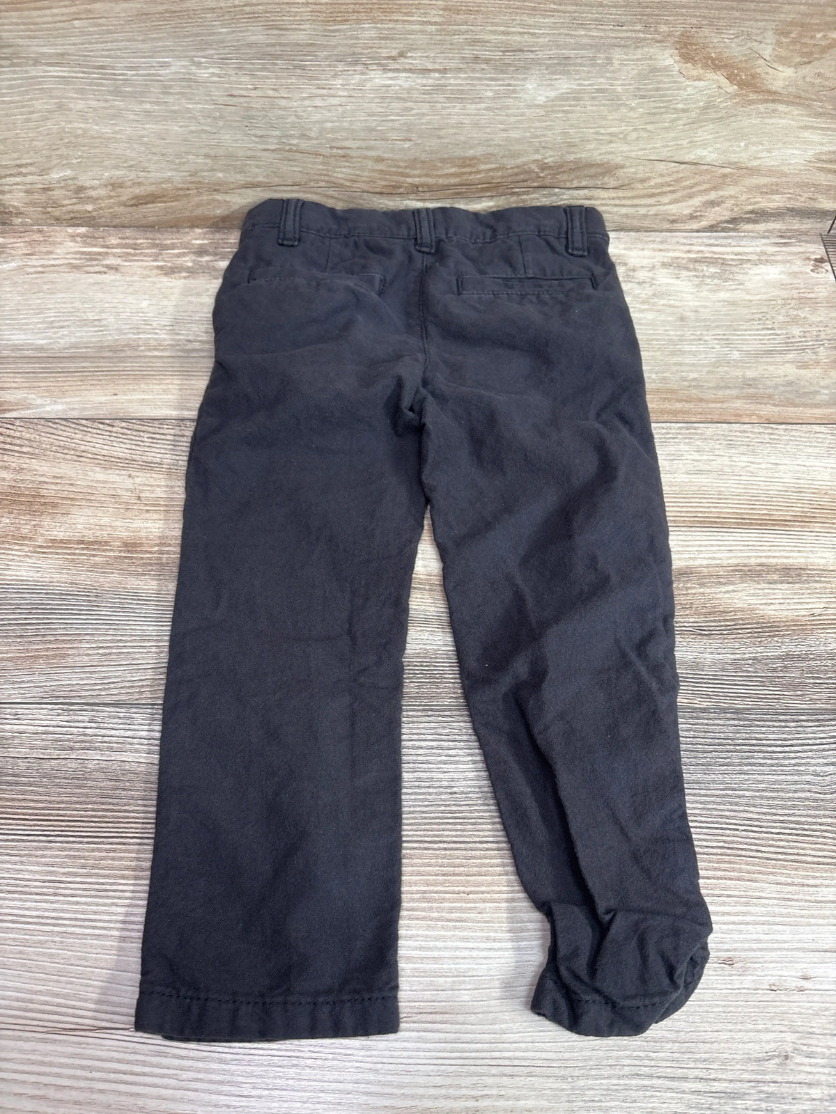 Rear view of grey Oshkosh kids' pants size 3T laid flat on a wooden background.