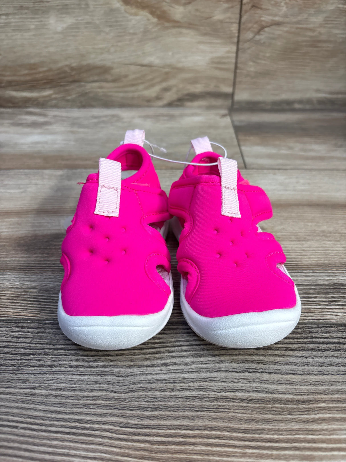 Front view of Cat & Jack water shoes in bright pink with white rounded soles, side cutouts, and pink pull tabs on wood