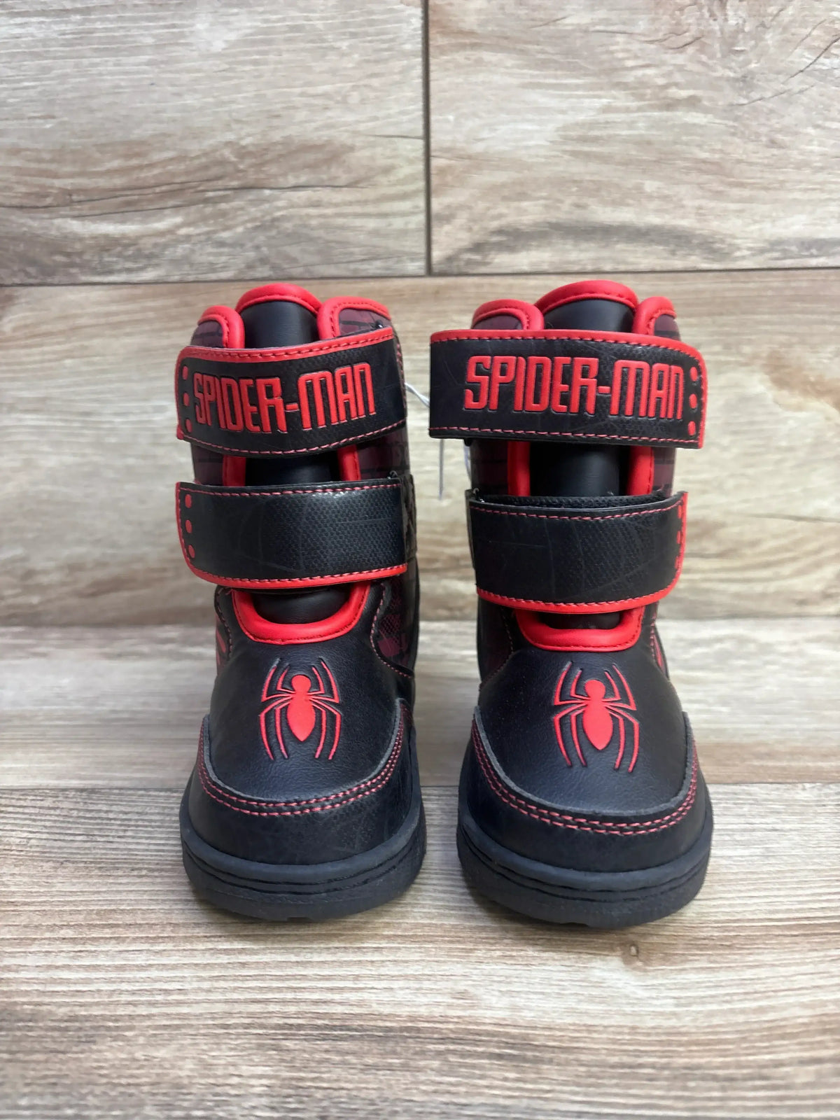 Black and red Spider-Man kids boots with spider logo and Velcro straps on wooden floor