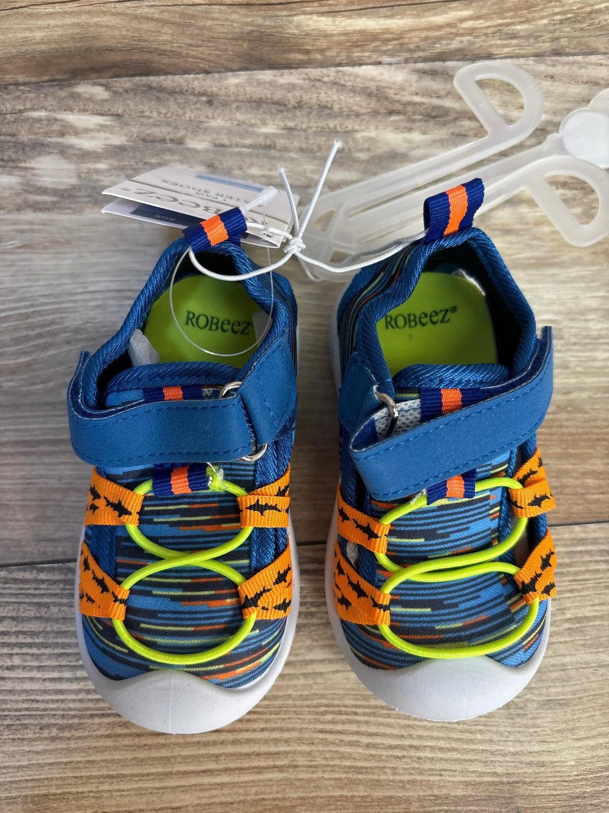 Top view of Robeez Gradient Mesh Water Shoes showcasing space dye shark pattern, Velcro straps and neon laces on wood floor