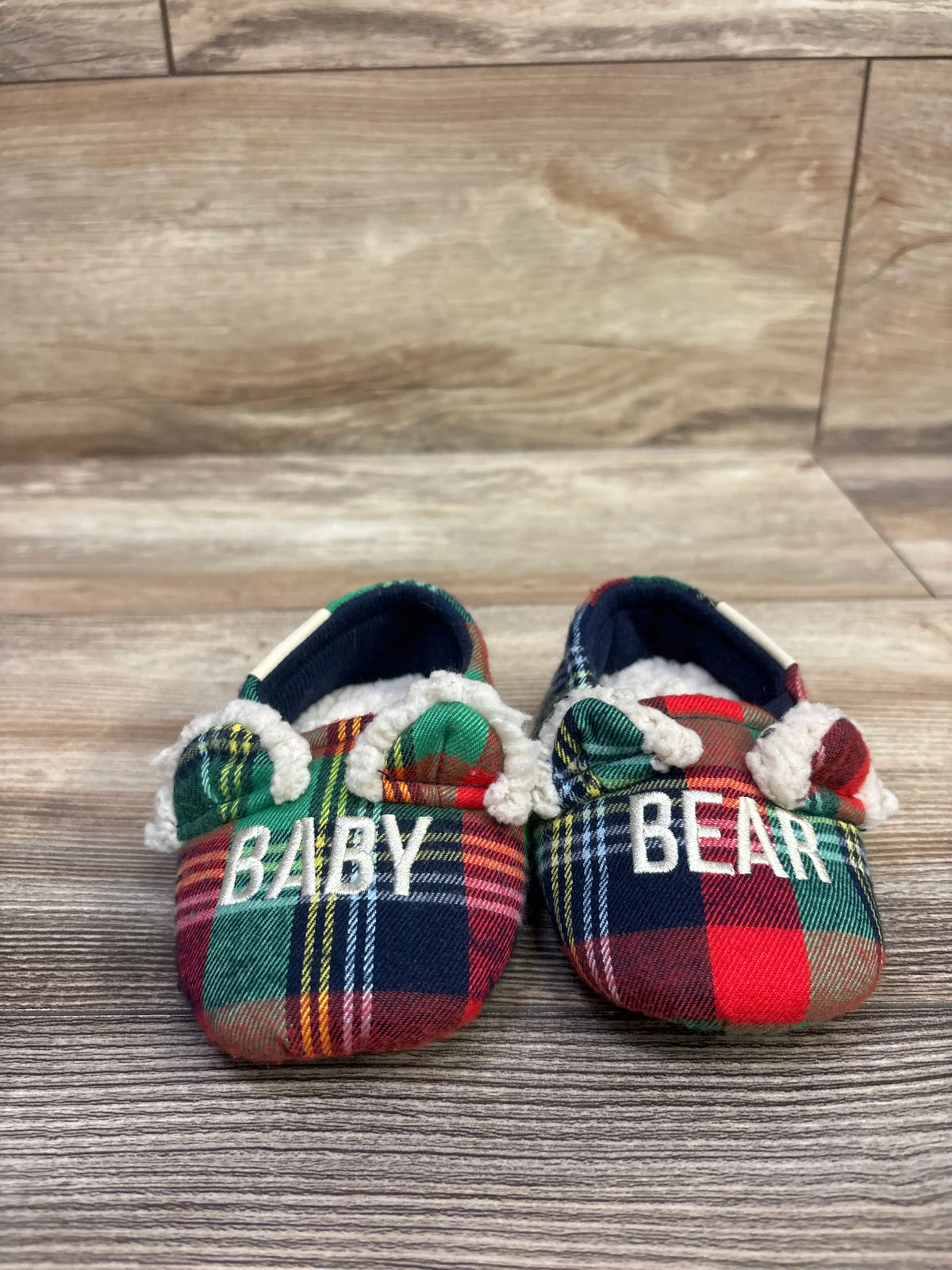 Front view of Dearfoams Baby Bear slippers, size 4C, with multicolor plaid fabric, fuzzy trim, and BABY BEAR lettering