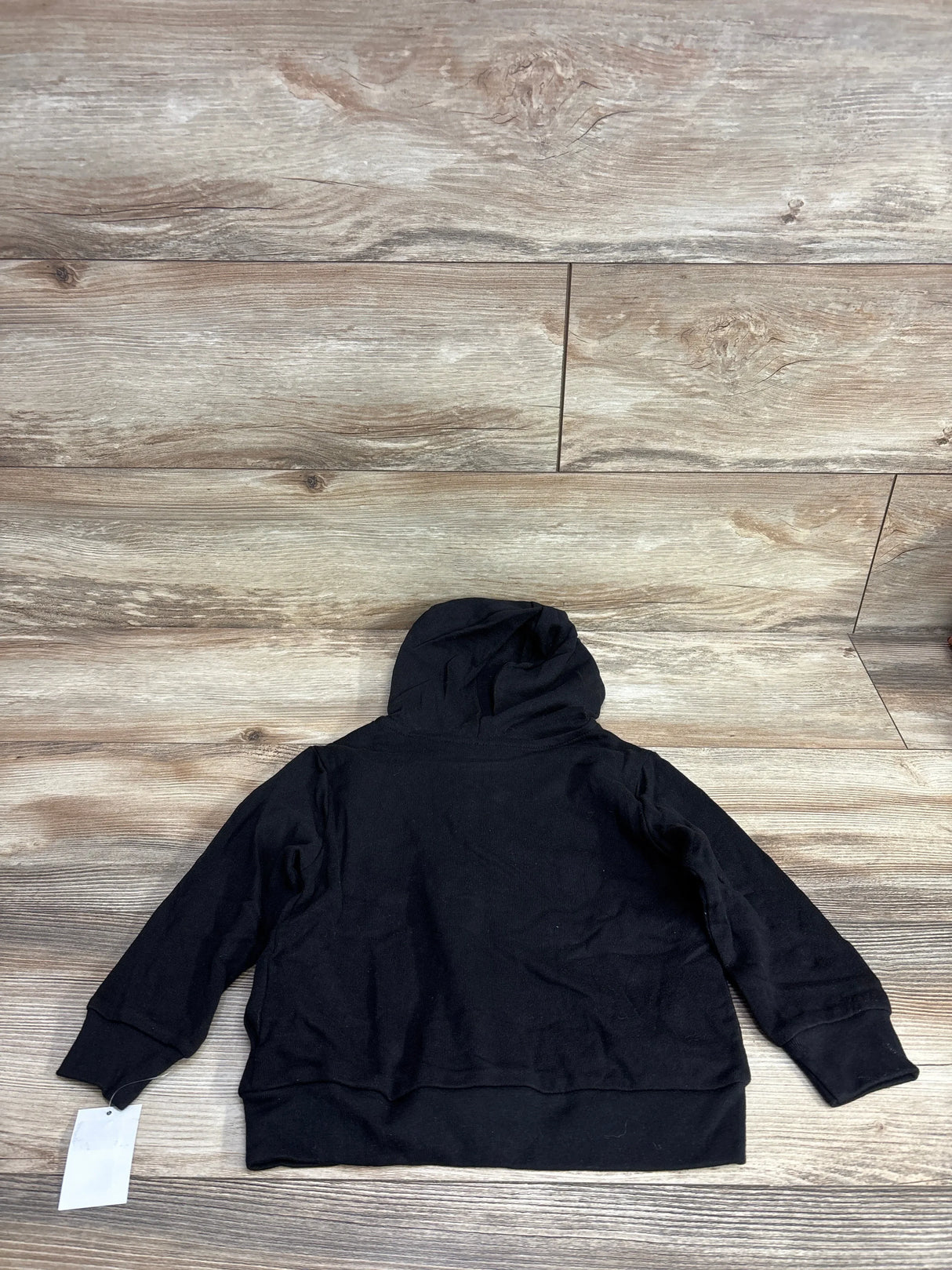 Black kids hooded sweatshirt laid flat on wood background, long sleeves, back view