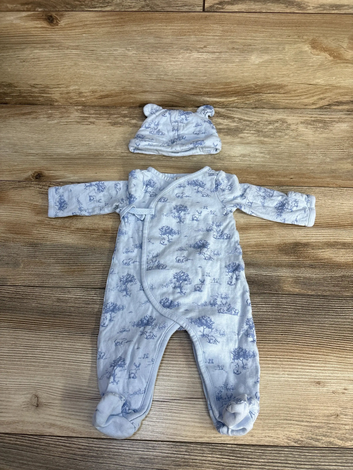 Blue baby onesie and hat set with animal print on wooden background