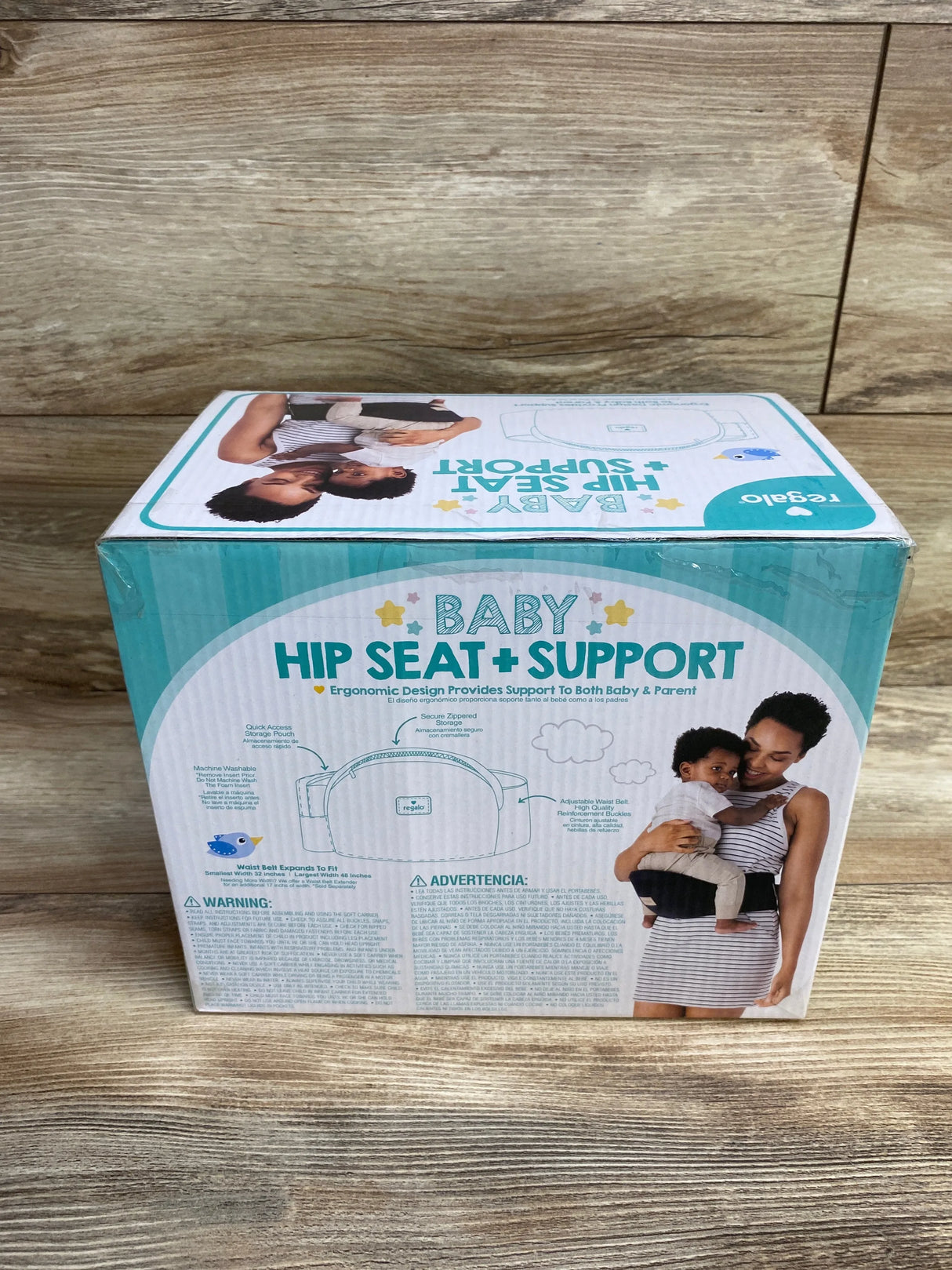Front view of Regalo Baby Hip Seat + Support box (Black, 15 to 25 lbs) showing hip seat illustration and photo of parent wearing carrier on wood floor