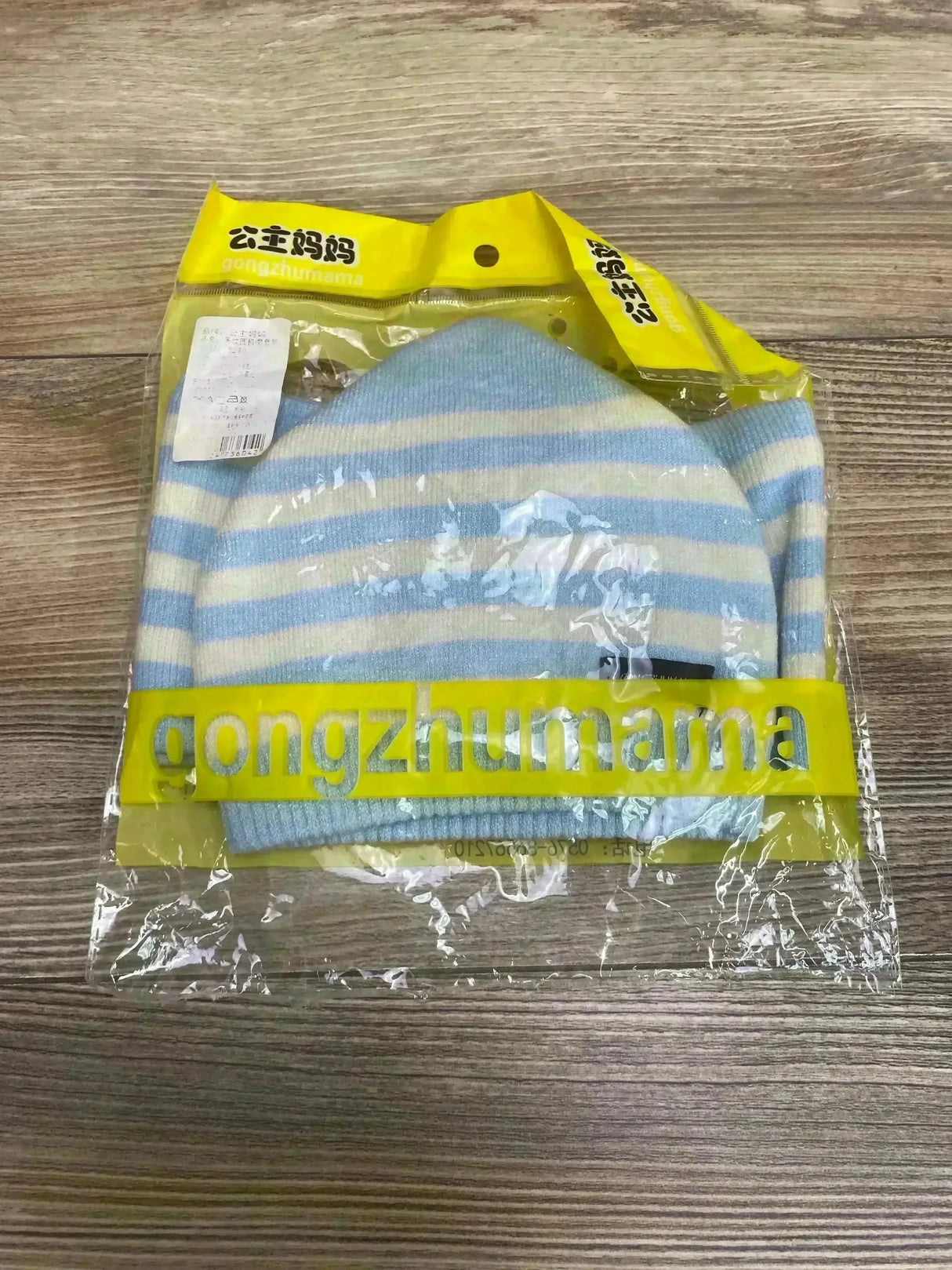 Front view of baby knit hat and matching scarf showcasing light blue and white stripes, packaged in clear plastic with yellow gongzhumama label on wood background
